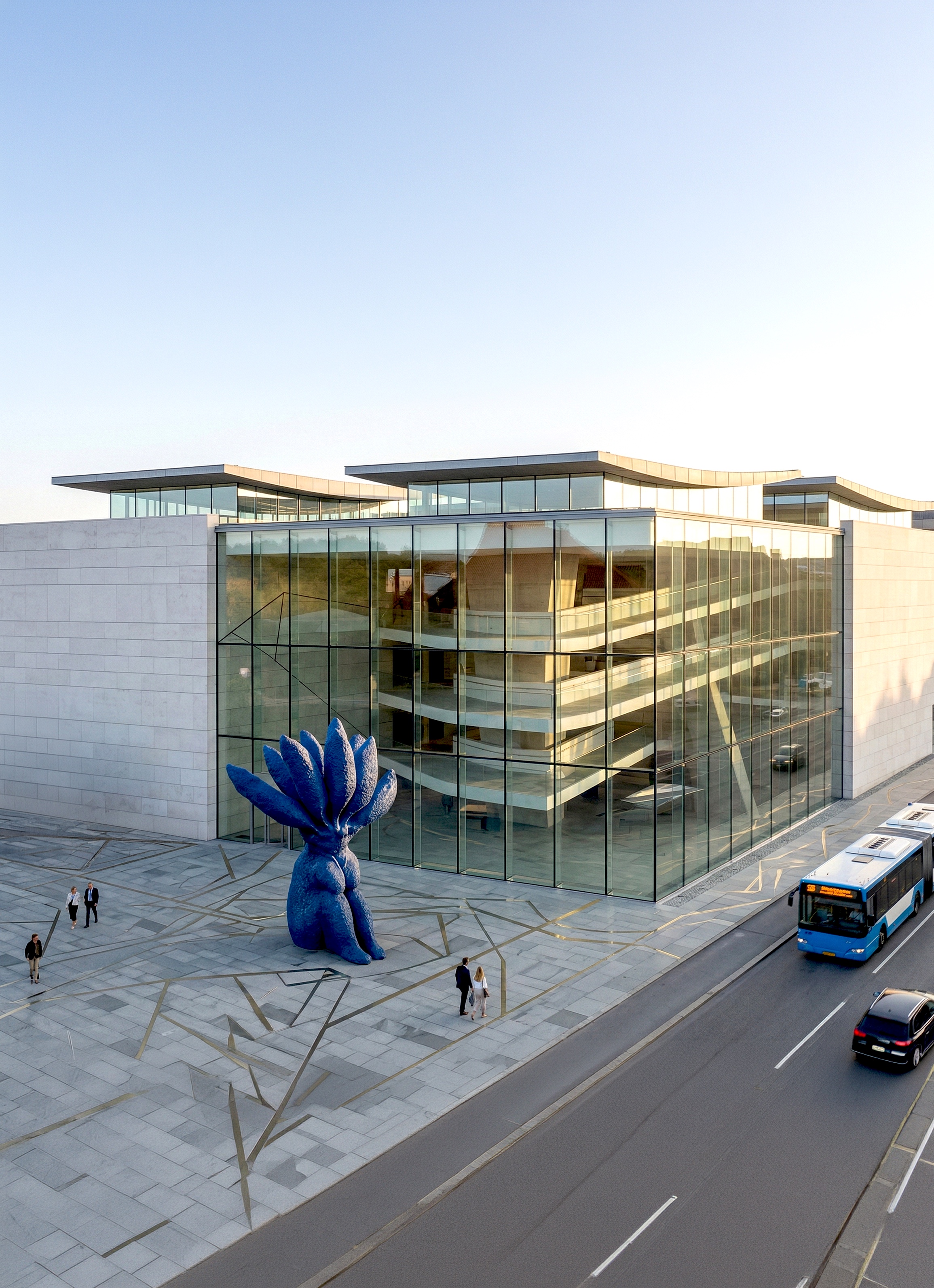 Corner view of the museum with a monumental blue sculpture at the entrance and multi-level gallery spaces visible through floor-to-ceiling glass