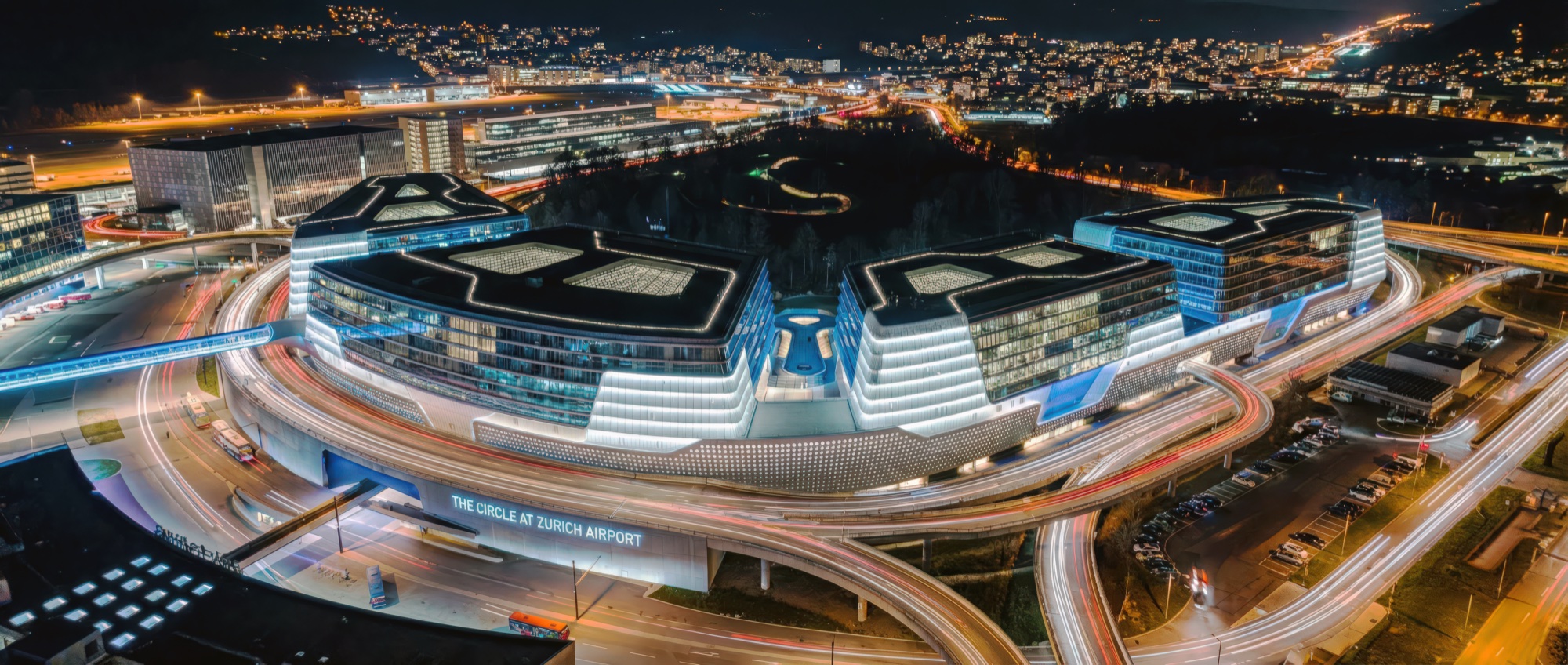 Night aerial panorama of The Circle complex illuminated alongside the airport runways and taxiways