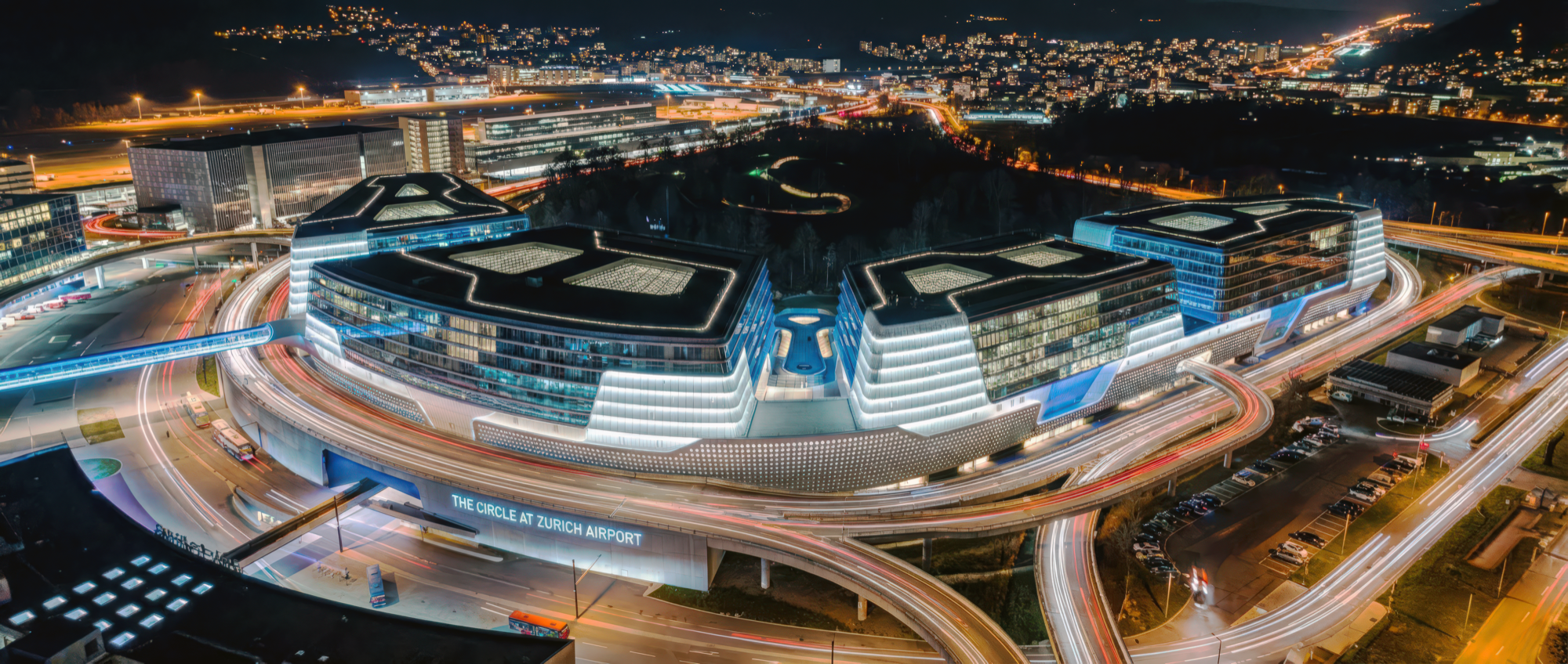 Night aerial panorama of The Circle complex illuminated alongside the airport runways and taxiways