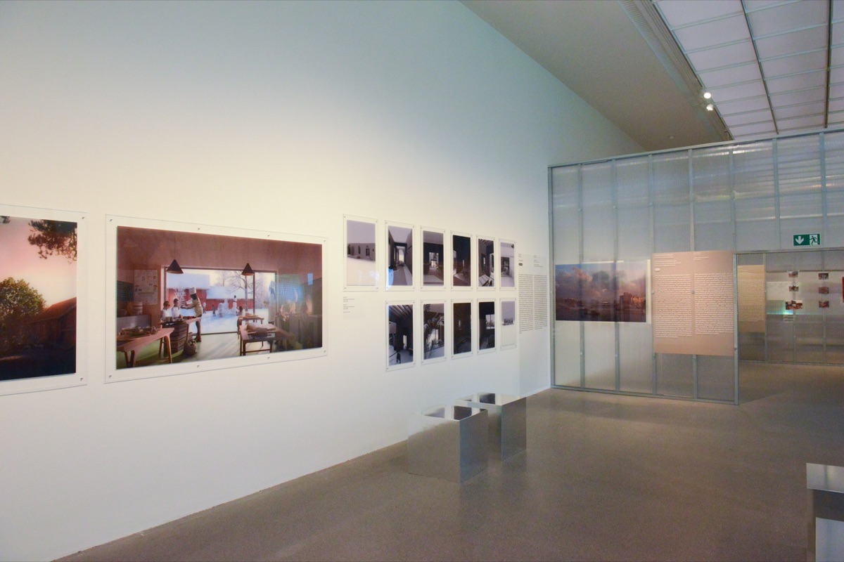 Exhibition gallery with large-format architectural renderings and photographs on white walls
