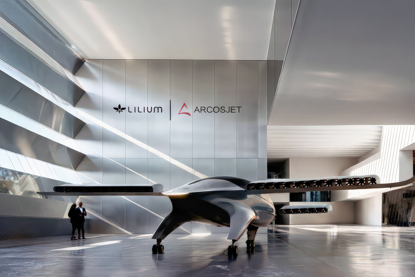 Double-height showroom with a Lilium eVTOL jet on display beneath Lilium and Arcosjet branding on a brushed steel wall, curved mezzanine above