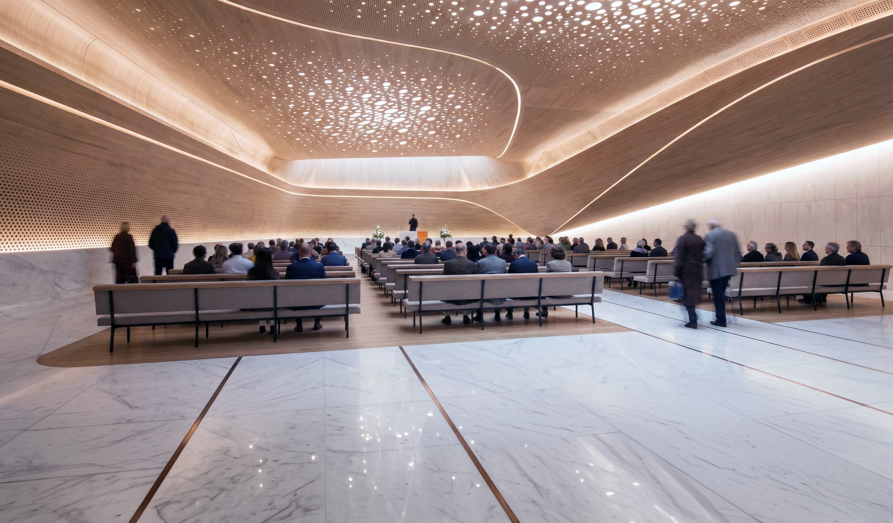 Beukenhof Crematorium ceremonial hall interior — perforated ceiling, warm timber tones, and marble floors