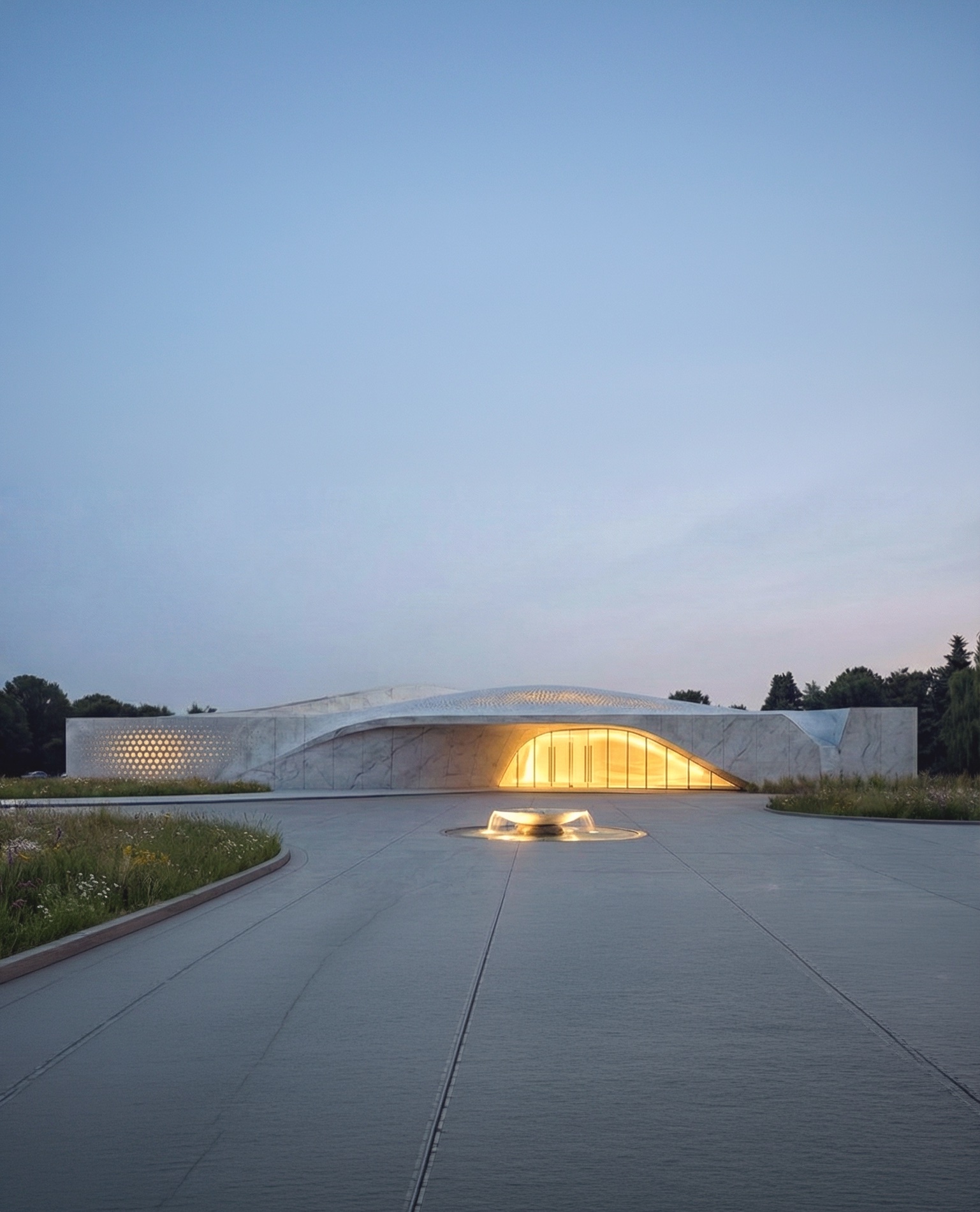 Beukenhof Crematorium approach at dusk — sculptural marble form with warm interior glow