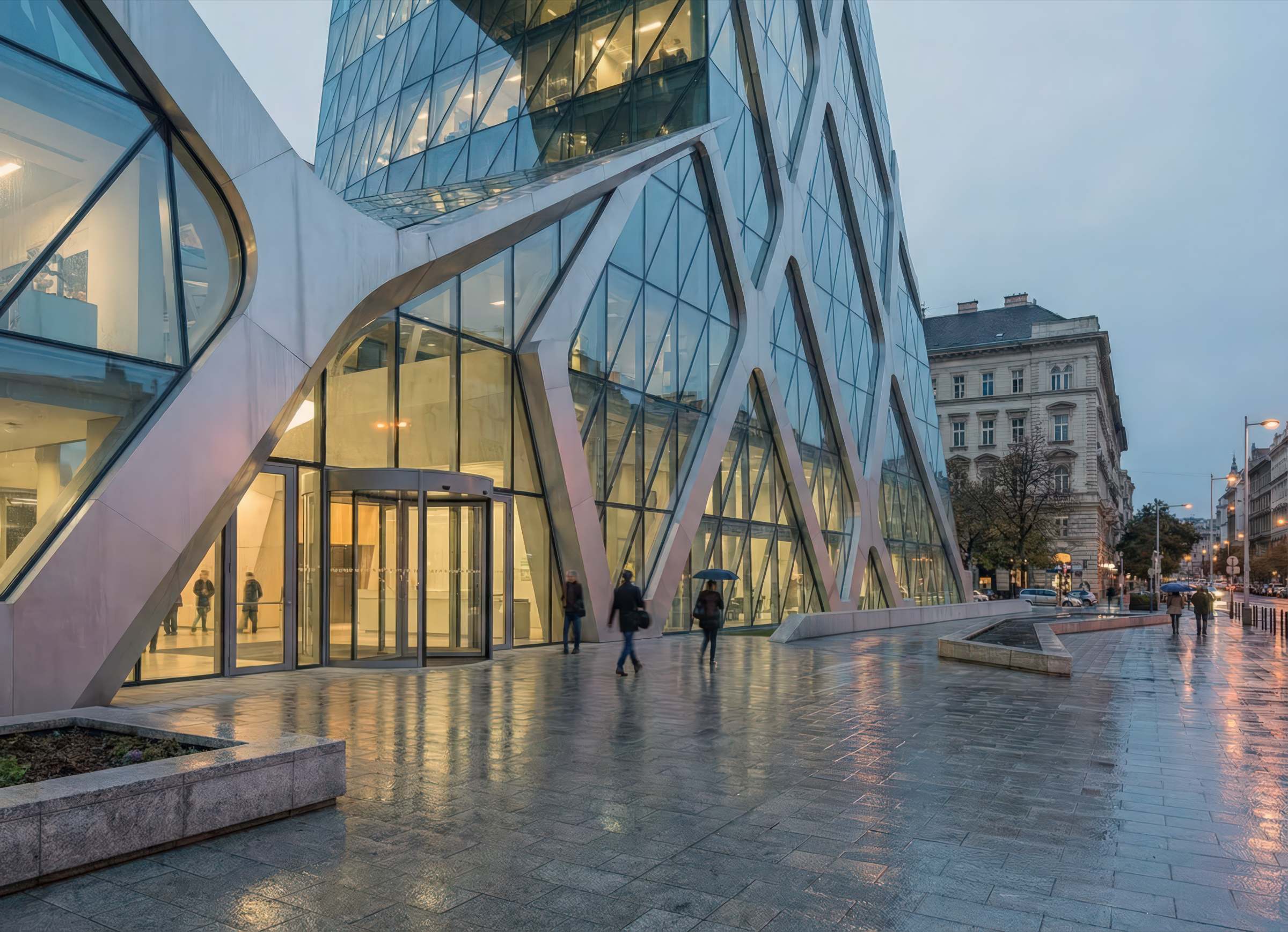 Street-level view at dusk of the tower base showing the diamond-grid structural facade meeting the sidewalk, a glass-enclosed lobby visible at ground level, pedestrians walking on wet pavement, and a historic Neoclassical building adjacent