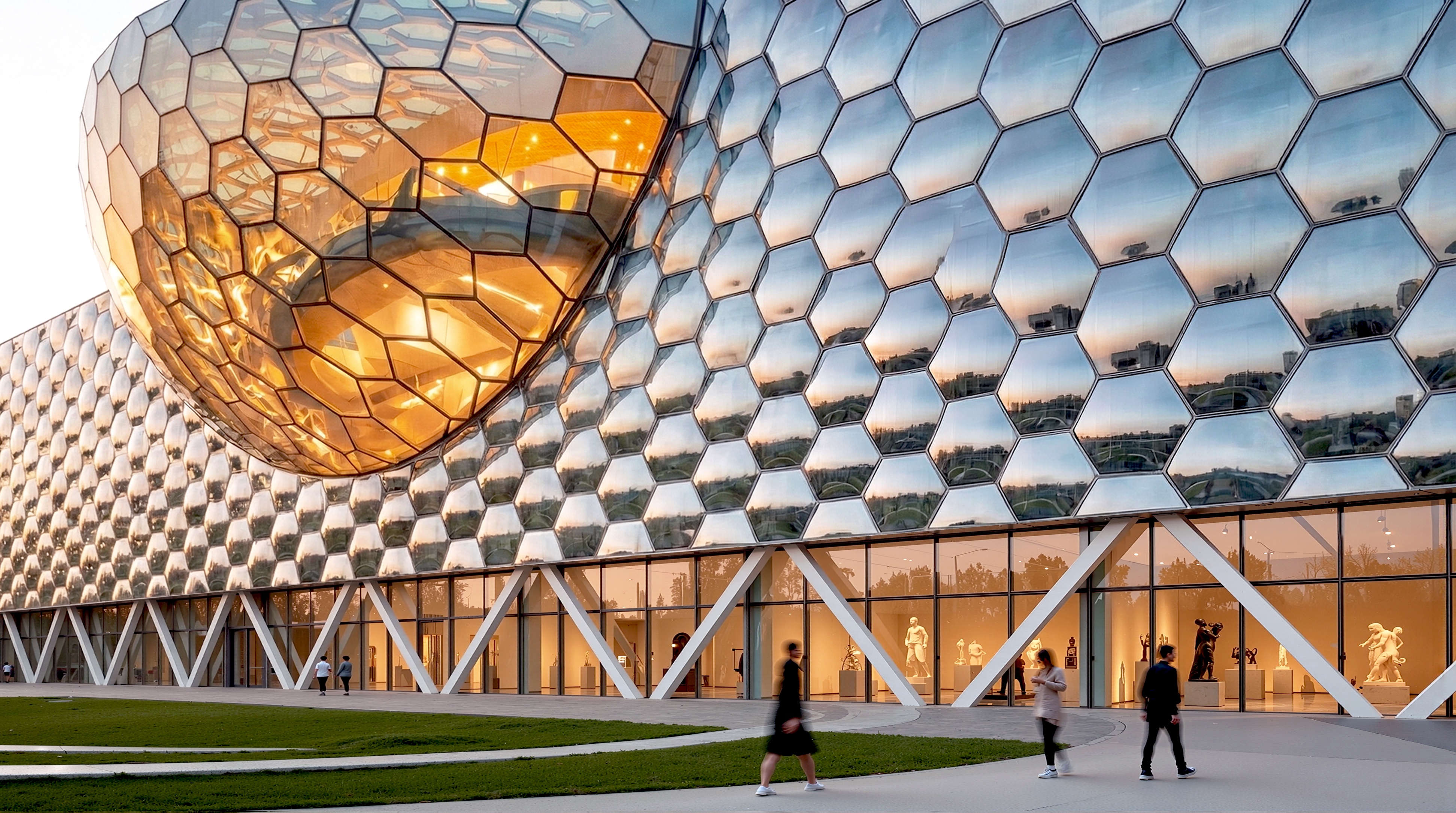 Gallery exterior at dusk with reflective hexagonal mirror facade and golden-lit spherical atrium element with pedestrians