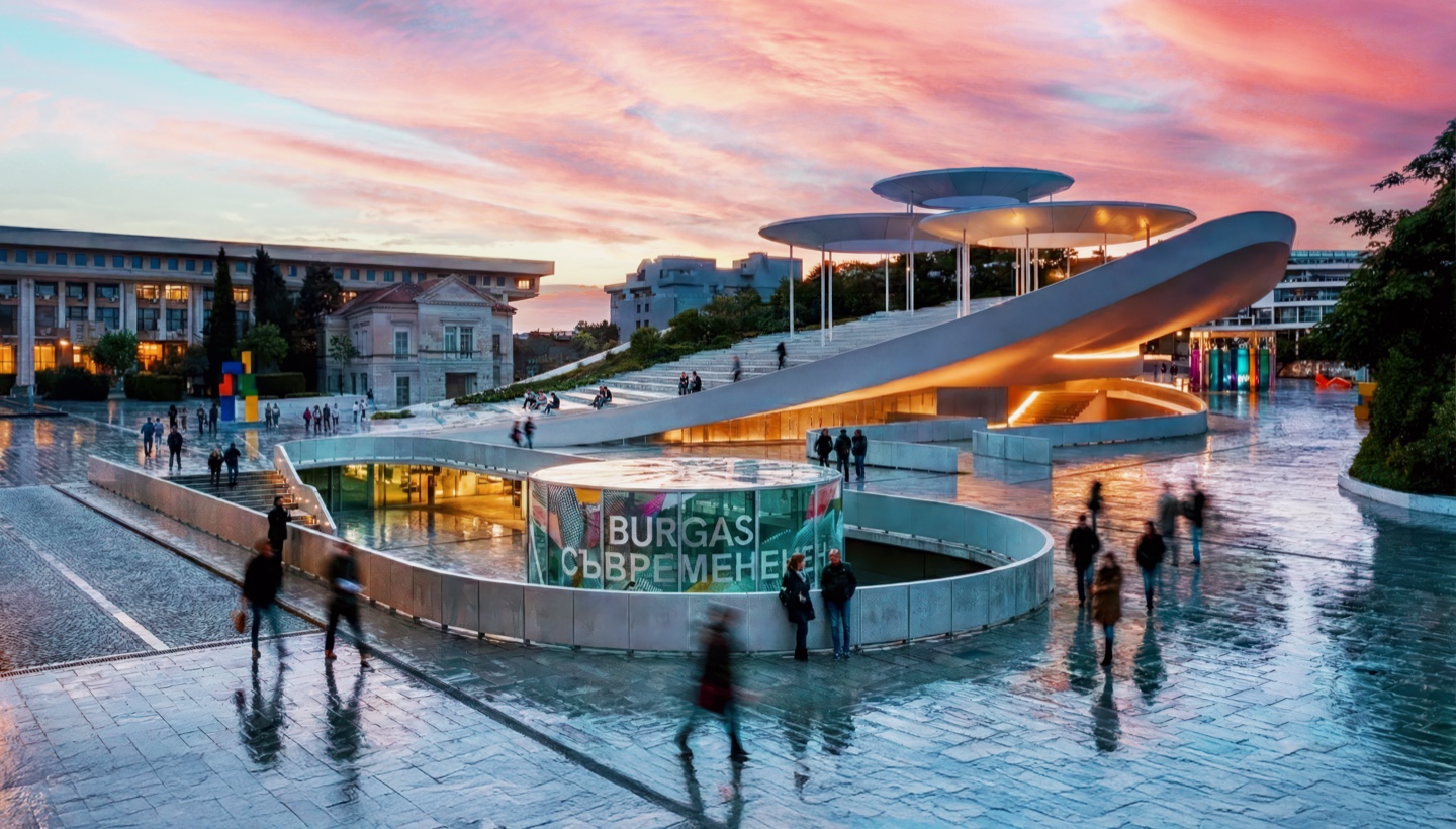 Exterior view of the center after rain with wet reflections on the plaza and the sculptural canopy forms above