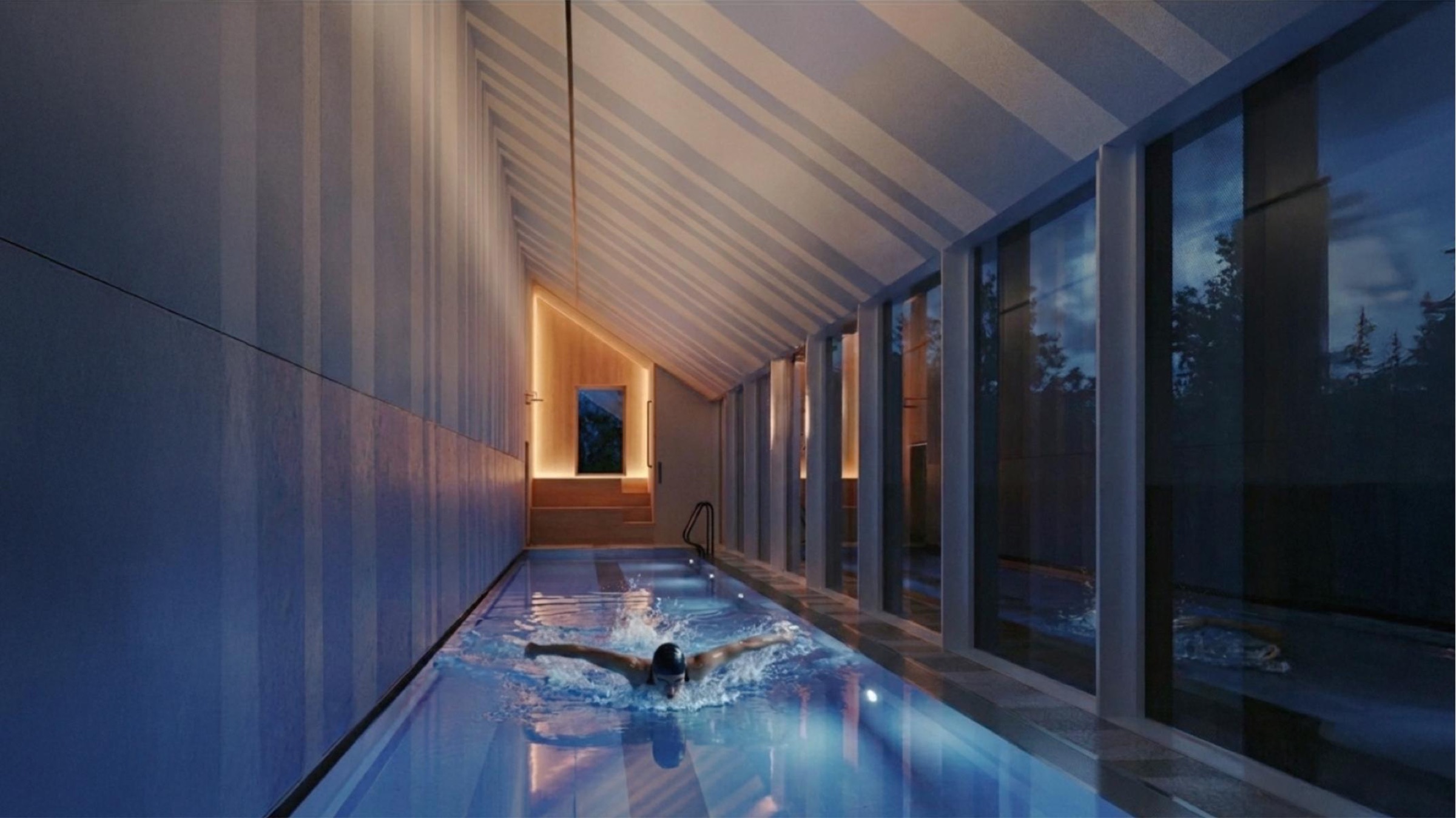 Butterfly Pool Pavilion — interior dusk view of the lap pool with a swimmer performing the butterfly stroke, striped wall panels and pitched ceiling above, full-height glazing opening to the wooded landscape