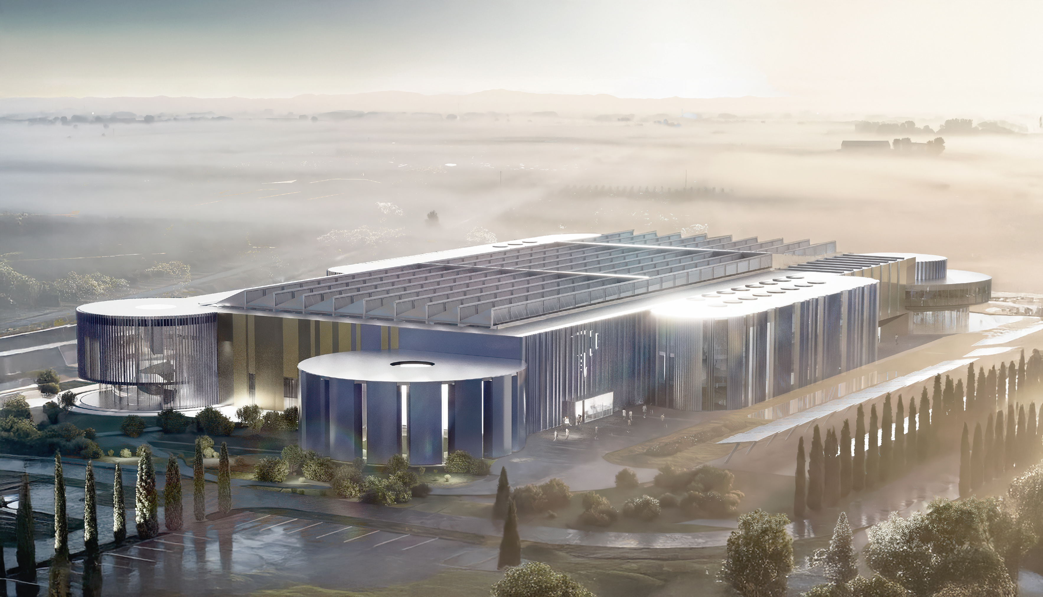 Aerial view of the Pinarello Factory and Headquarters campus at dawn, with mist on the horizon and cypress trees lining the entrance road