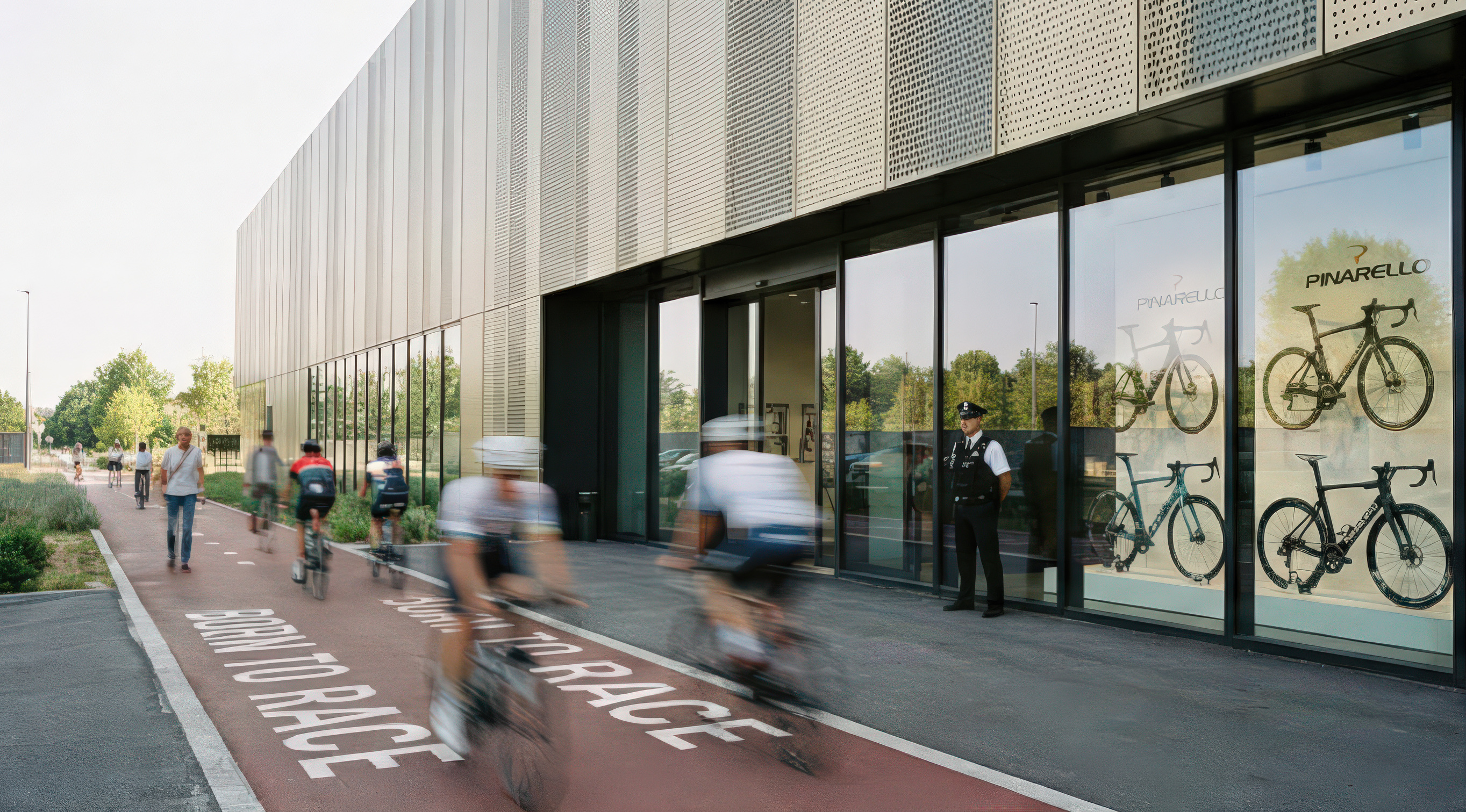 Cyclists riding along the red 'Born to Race' track parallel to the perforated metal facade, with Pinarello bicycles visible in the building's display windows