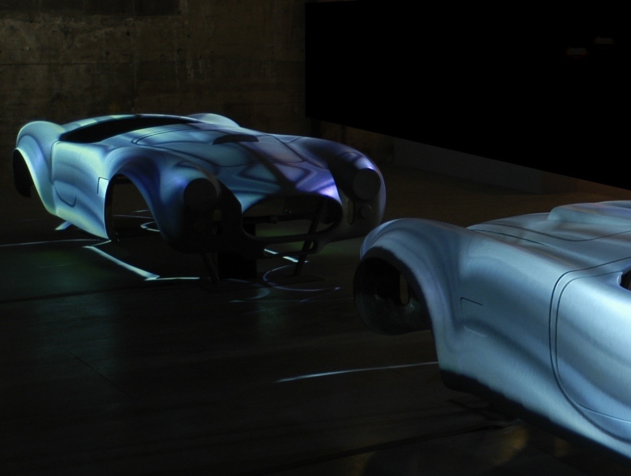 Close view of the Ascape car body forms with projected digital animations playing across their surfaces