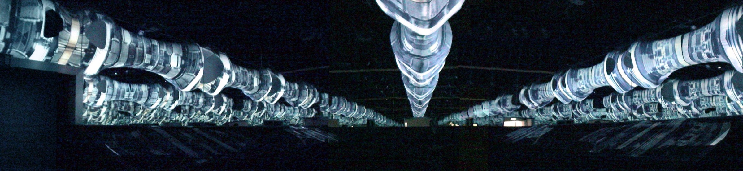 Panoramic view of Fluxspace 3.0 — biomorphic armatures converging overhead with video projections of abstracted city skylines reflected in mirrored surfaces