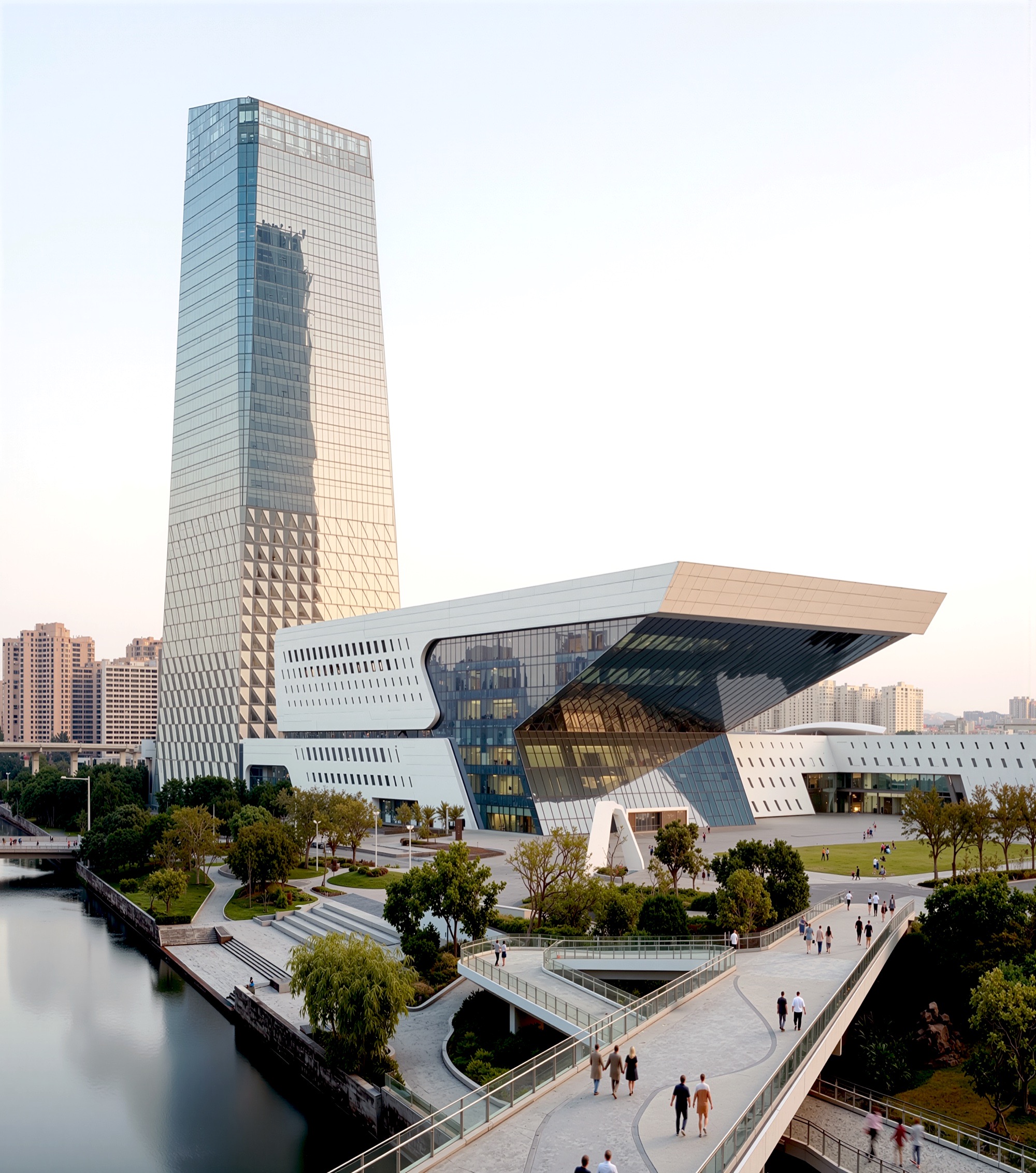 Portrait view of the tower and performing arts center from across the canal, with pedestrian bridges, landscaped waterfront, and warm evening light