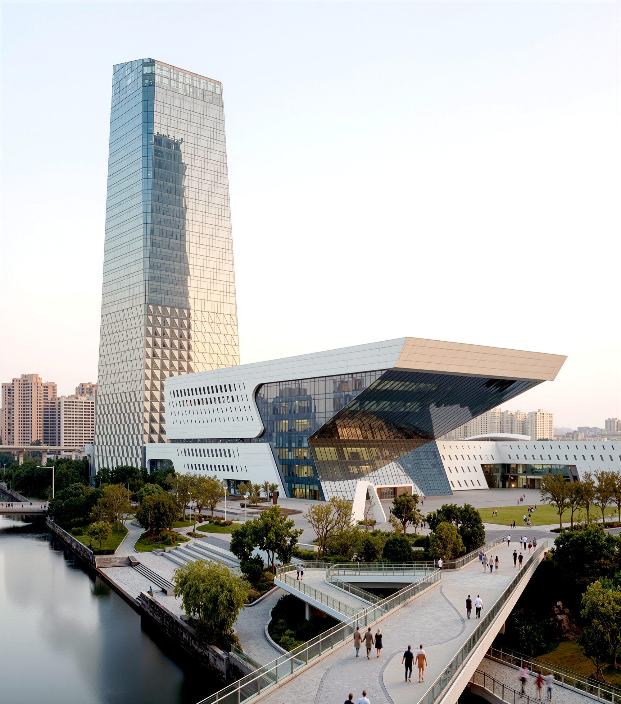 Portrait view of the tower and performing arts center from across the canal, with pedestrian bridges, landscaped waterfront, and warm evening light