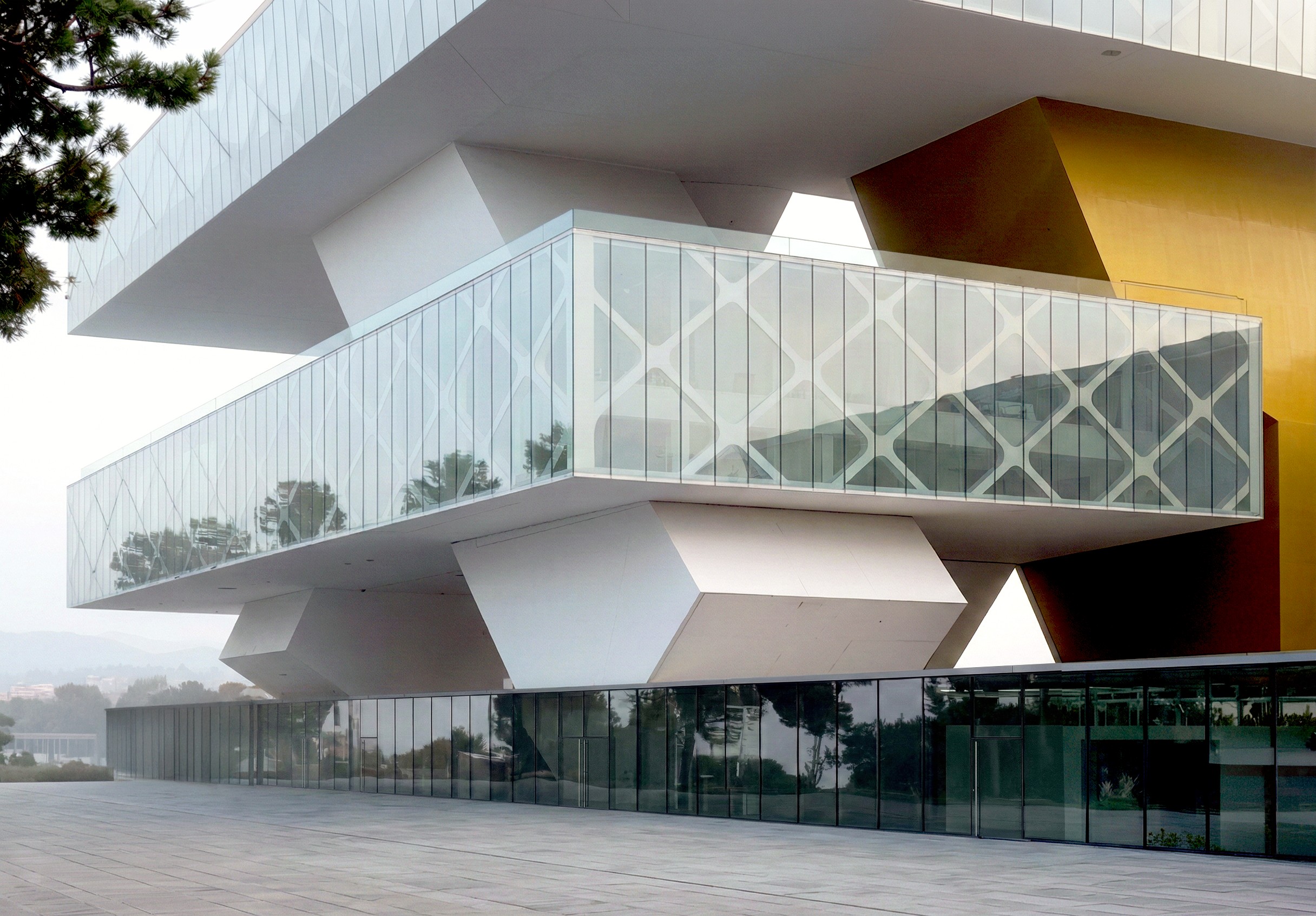 Exness Headquarters facade detail — diamond-lattice structural glazing with faceted white volumes and yellow accent panels