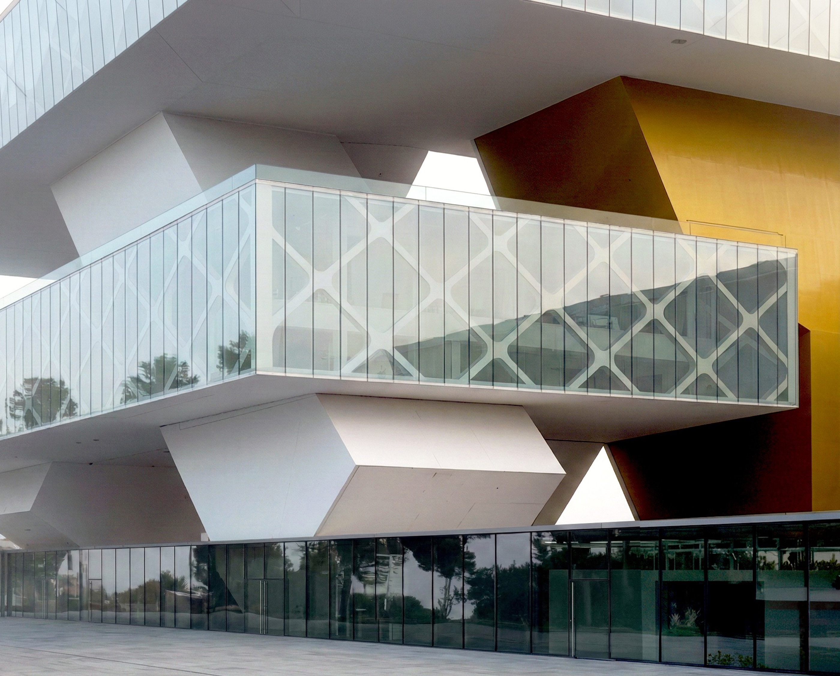Exness Global Headquarters, diamond-lattice structural glazing with faceted white volumes and a yellow accent volume at upper right.