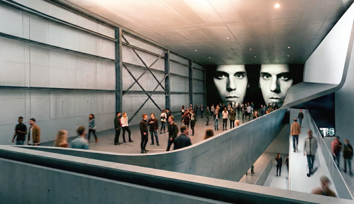 Industrial-scale exhibition hall with exposed steel structure, large projected portrait artworks, and a sweeping concrete ramp with visitors