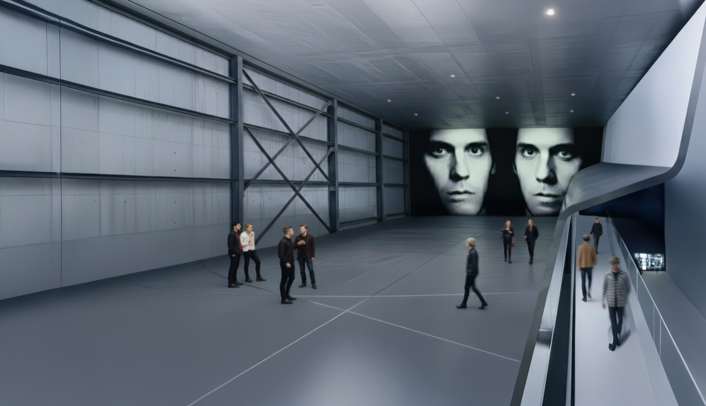 Expansive upper gallery space with steel cross-bracing, large projected face artworks on the far wall, and a ramped walkway along one side