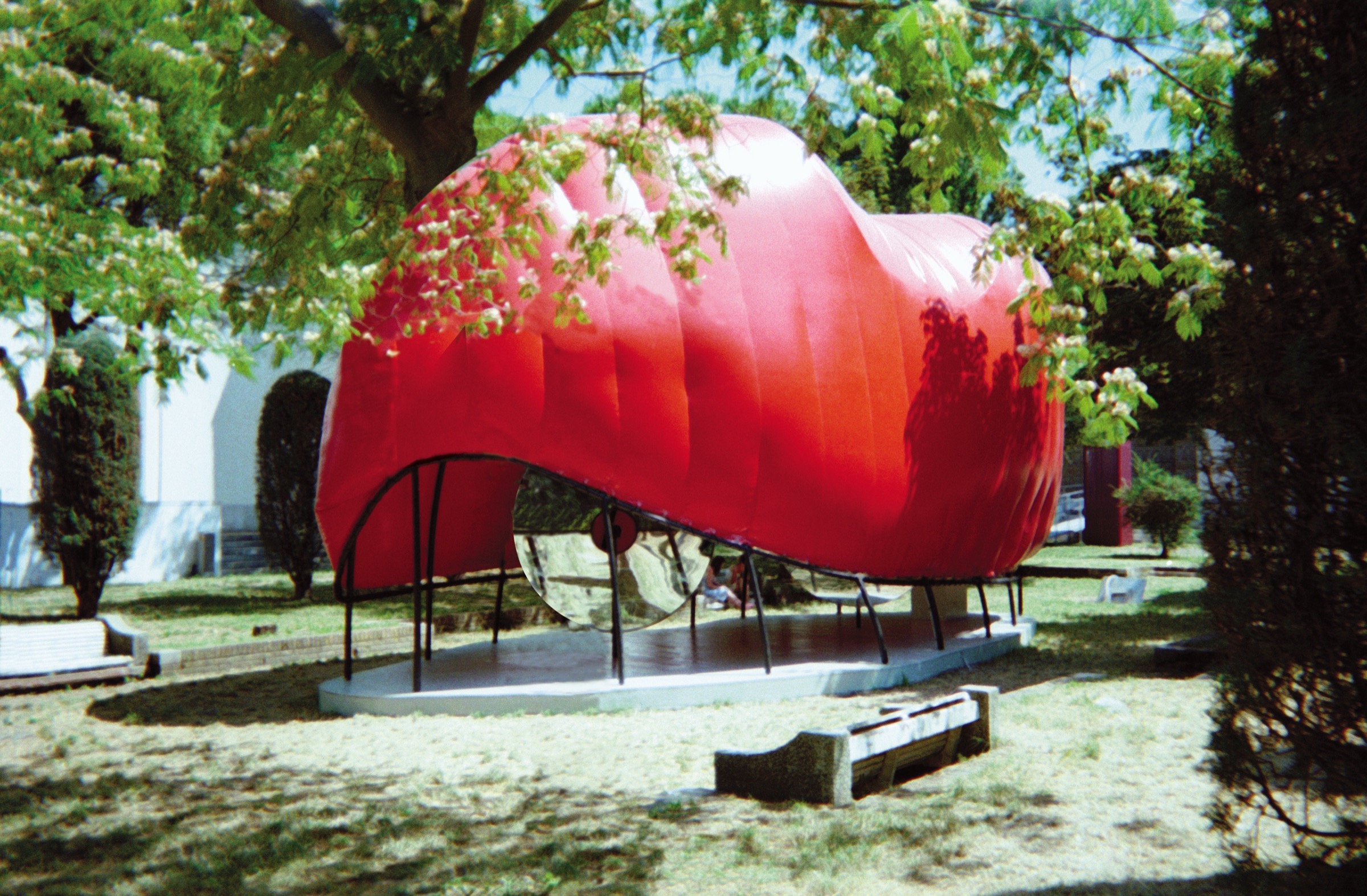 FluxSpace 2.0 — exterior view of the red pneumatic pavilion in the Giardini among the trees
