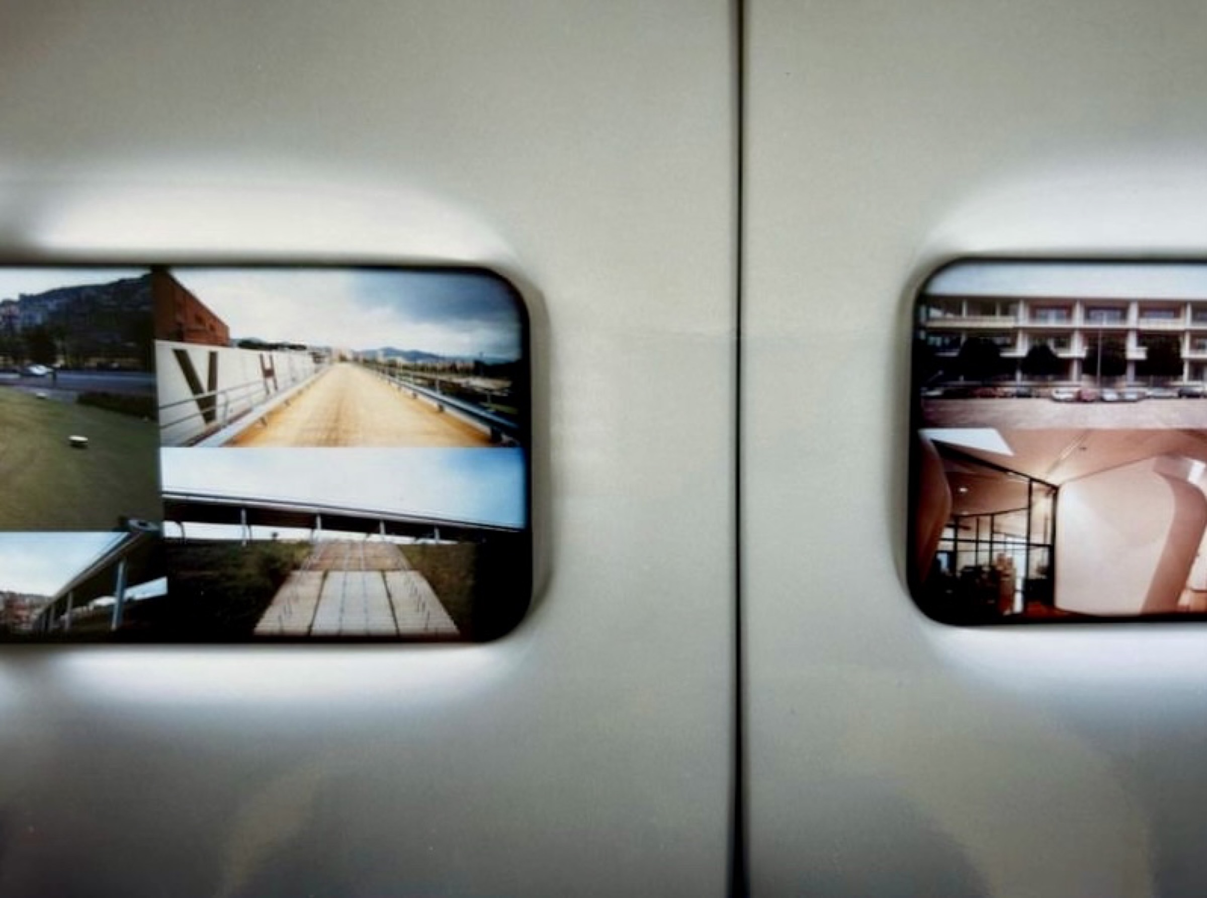 Detail of two smaller embedded screens showing architectural landscape and interior imagery within the white sculptural surface