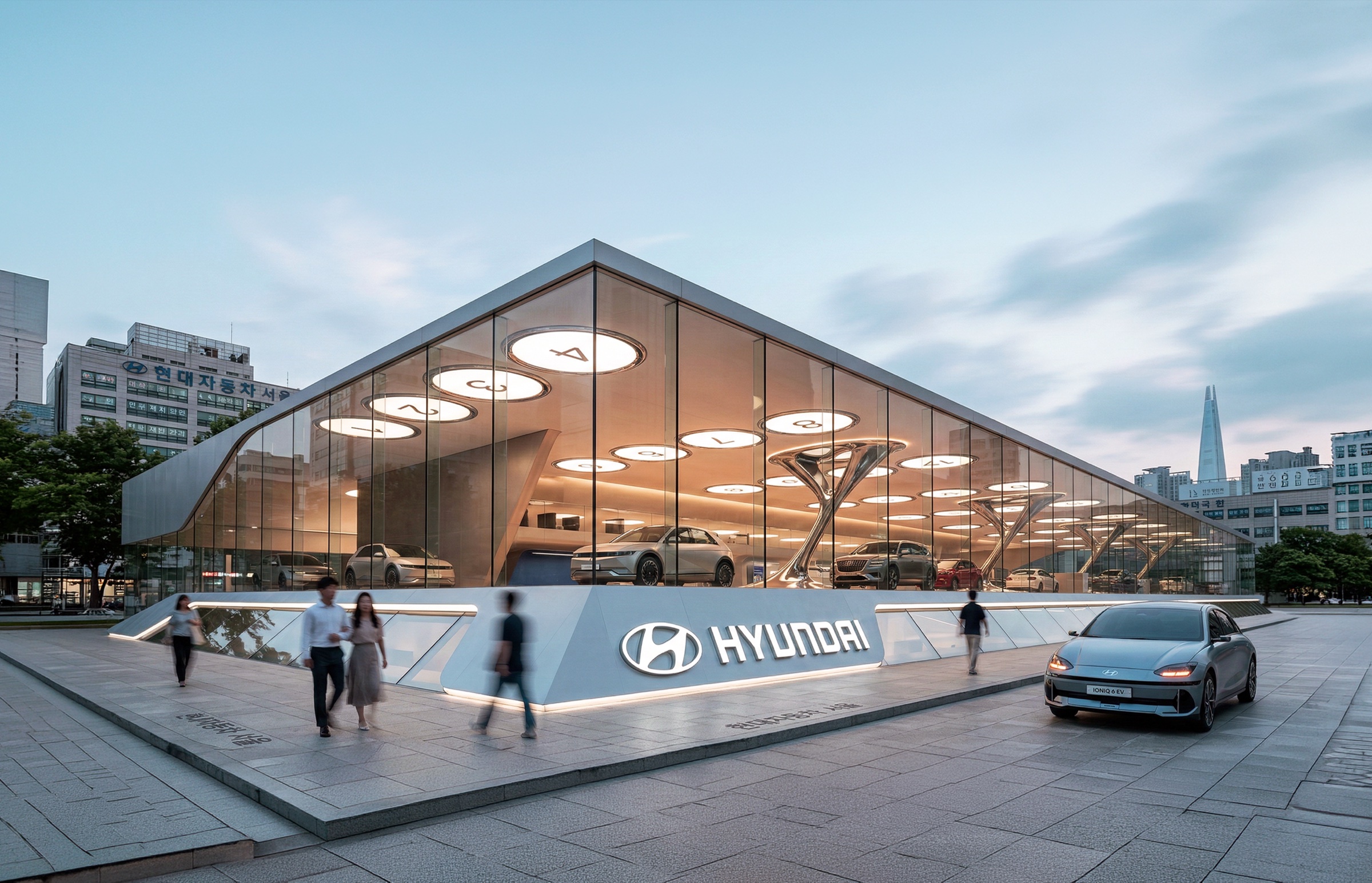 Street-level exterior view of the Hyundai showroom at dusk with its angular glass facade, illuminated circular ceiling lights, Hyundai branding, and pedestrians passing by