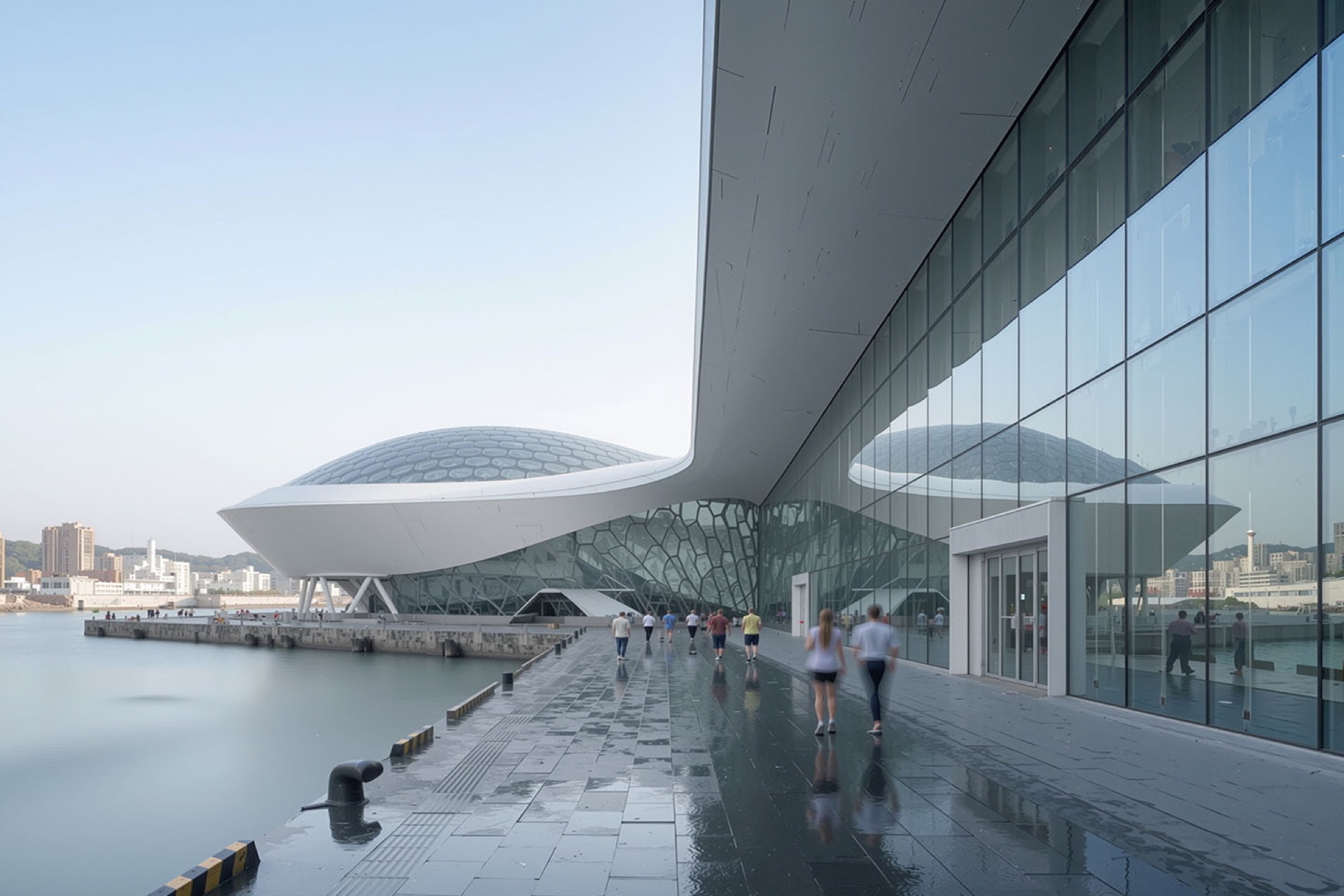 Waterfront promenade along the harbor edge with pedestrians, the honeycomb dome and sweeping glass curtain wall of the terminal beyond