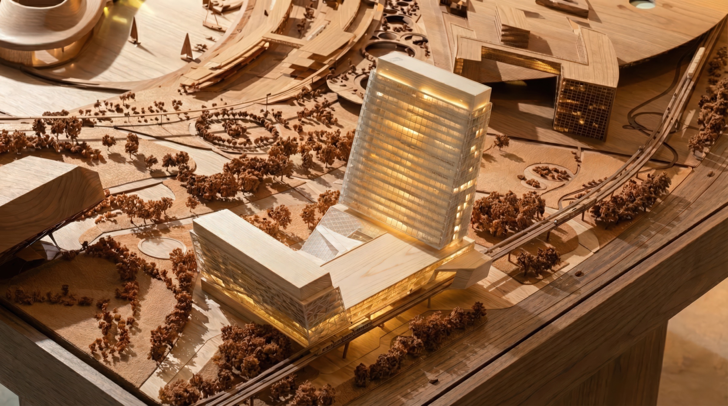 Physical architectural model in basswood showing the Langham Place tower and podium within the Da Wang Shan resort masterplan context, illuminated interior volumes and surrounding landscape