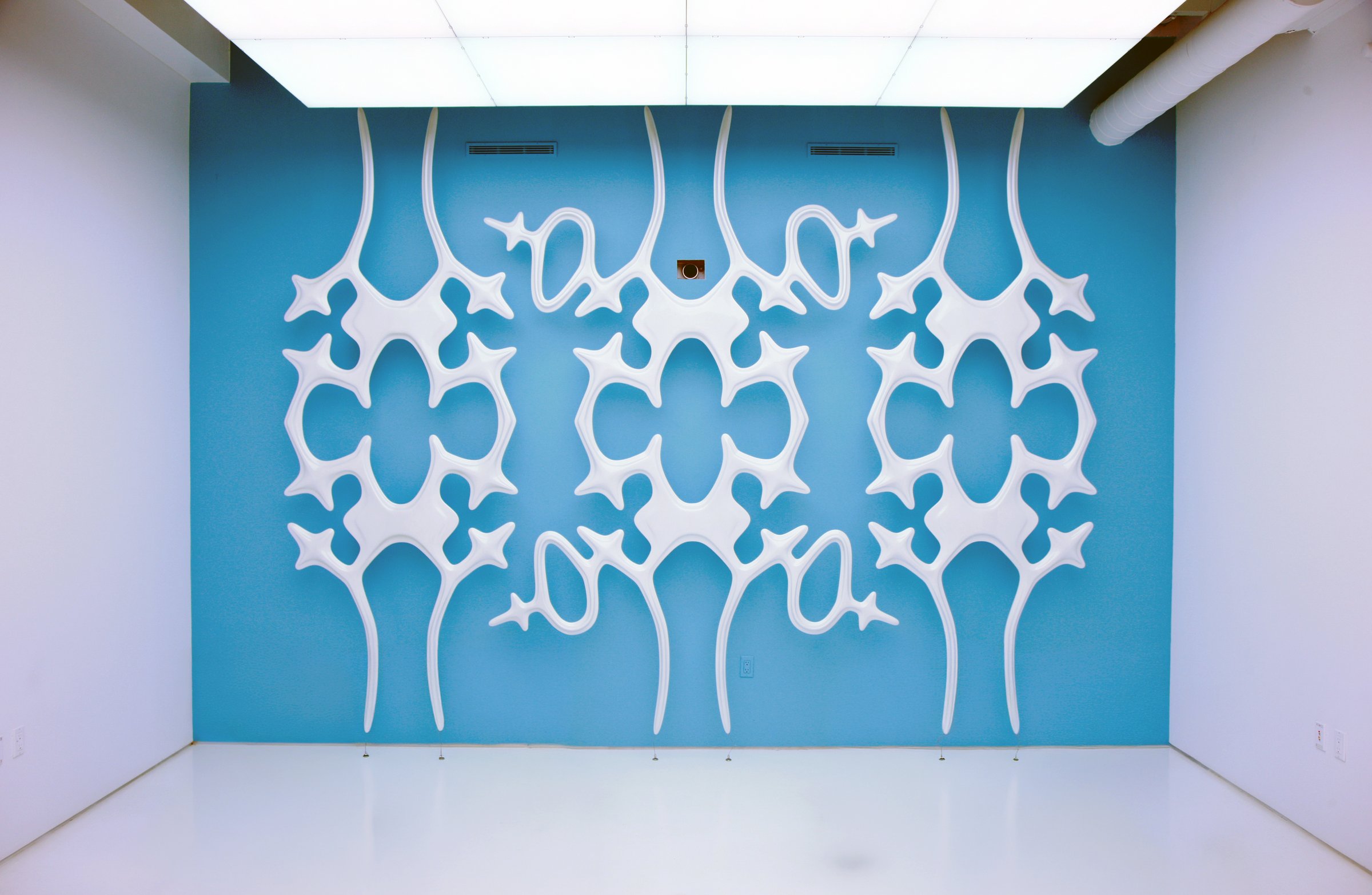 Mantella Screening Sculpture installed at Asymptote's studio — white phosphorescent lattice forms mounted on a blue wall