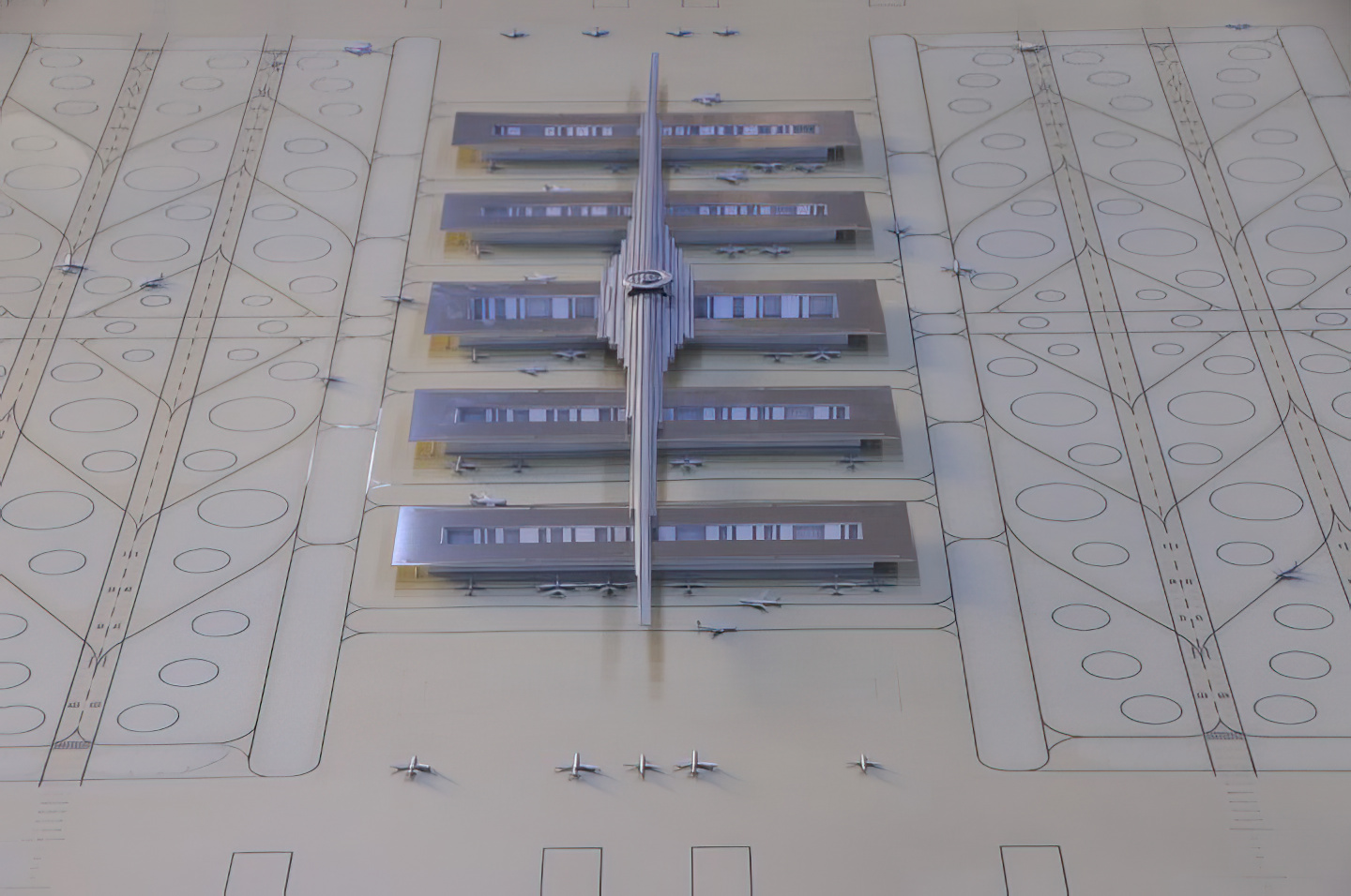 Aerial view of the physical model showing the full airport layout with symmetrical terminal concourses, central spine, runways, and taxiways