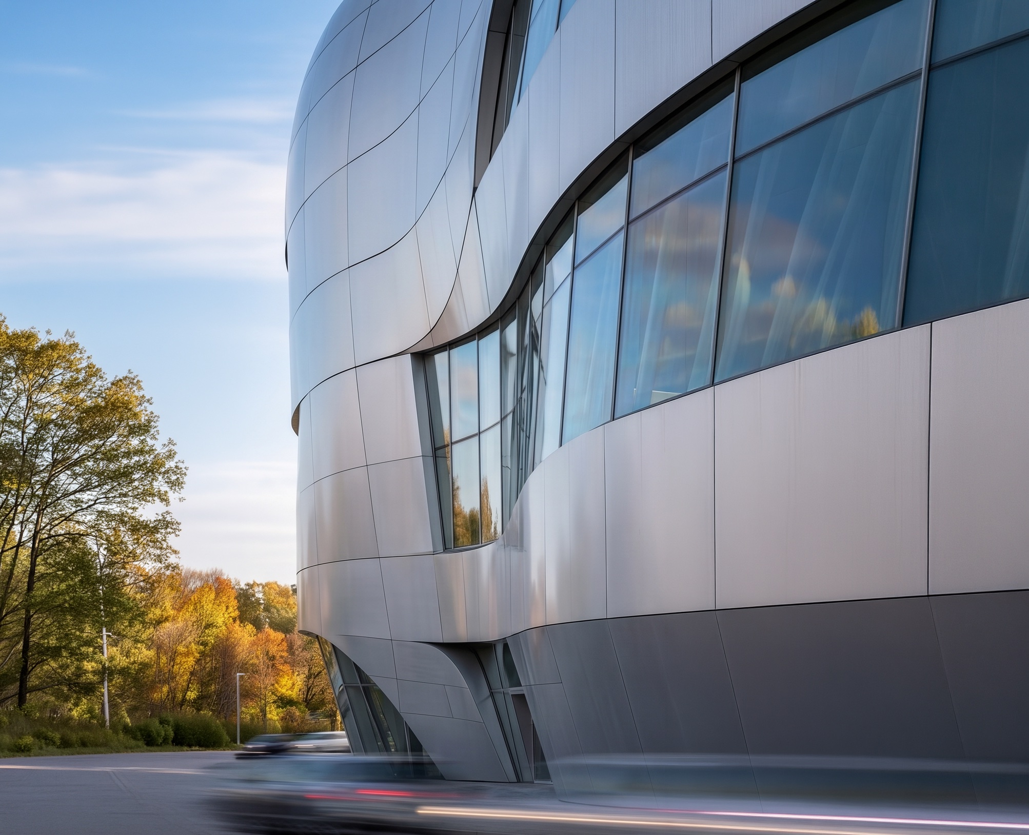 Exterior view of the Mercedes-Benz Museum competition entry showing a curved aluminium-clad envelope with vehicular silhouette, large window apertures, and autumn trees in the foreground