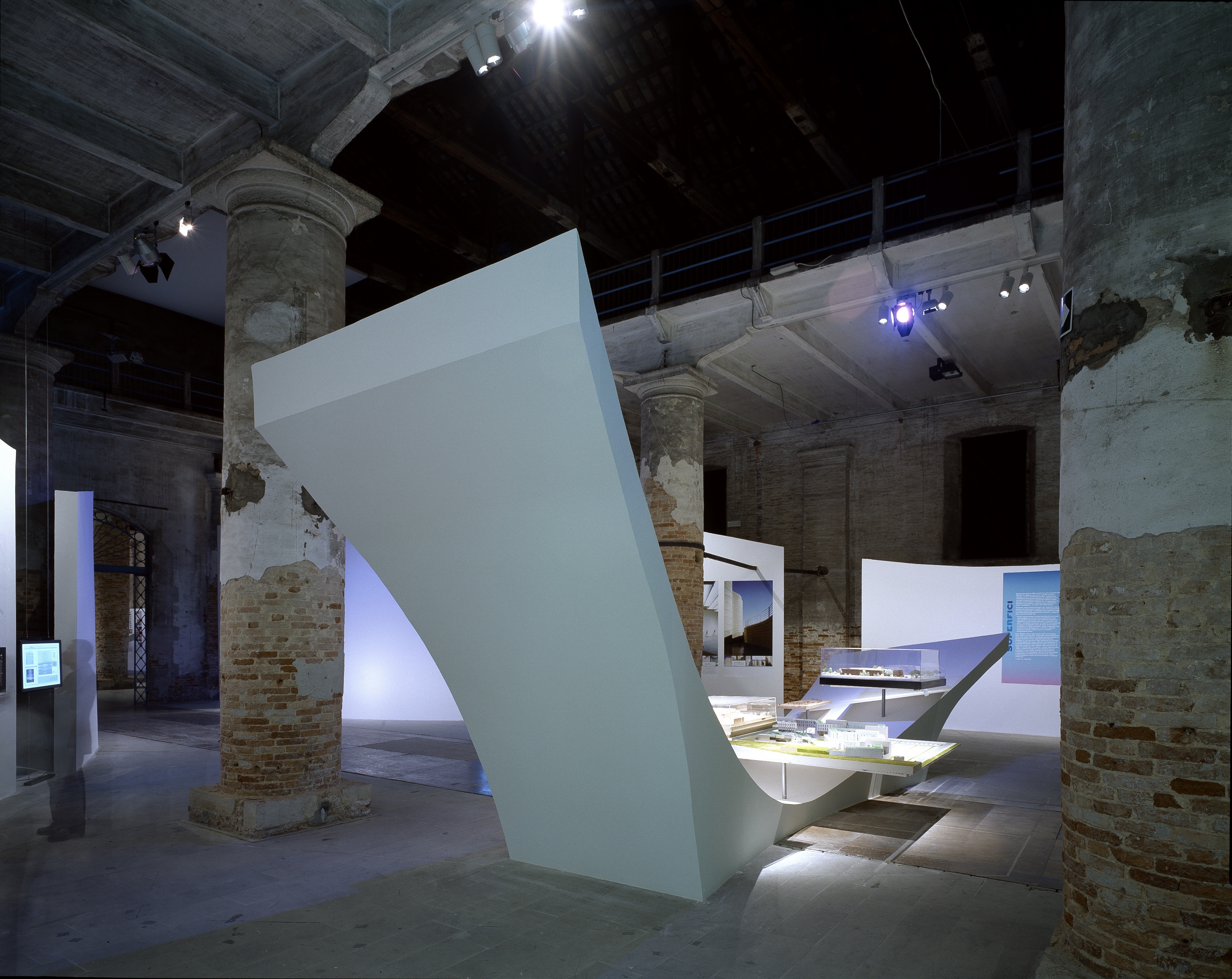 View from the entrance of the Metamorph exhibition — illuminated white surfaces stretching into the depth of the Arsenale