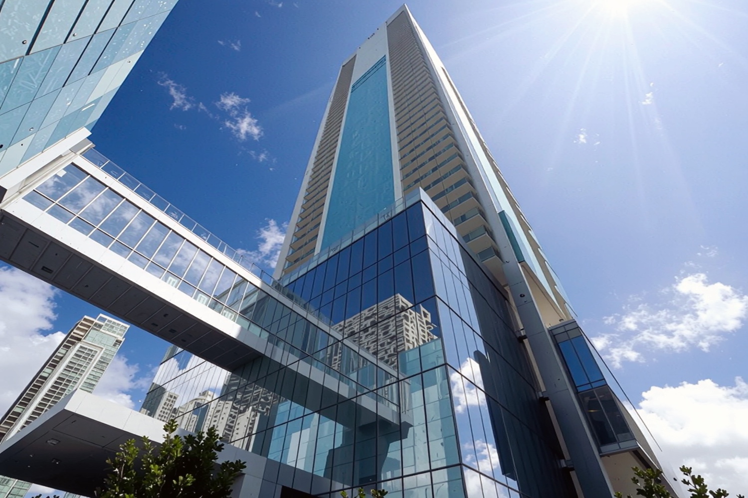 Low-angle view of the Missoni Baia glass tower with sunlight reflecting off the facade and Miami skyline in the background