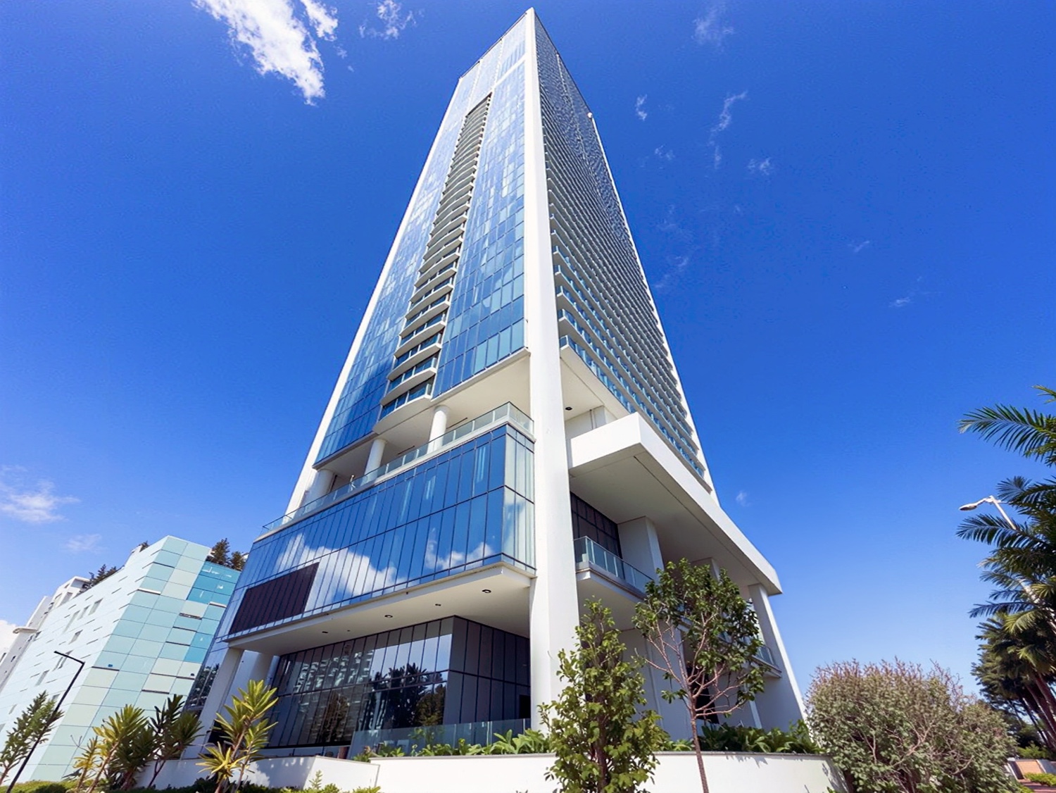 Ground-level perspective of the Missoni Baia tower showing its distinctive tapering form with palm trees and blue sky