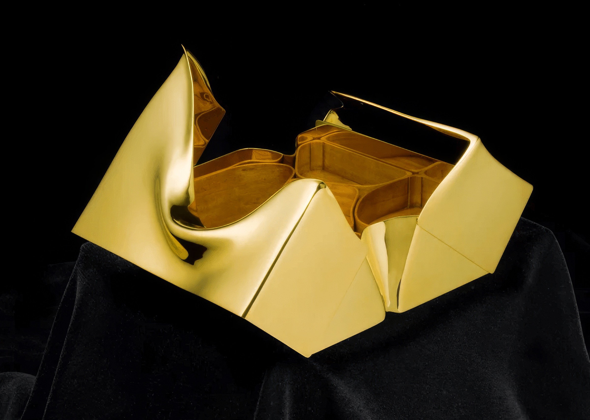 Mnemos 01 opened on black velvet — faceted gold exterior with flowing lid element revealing satinwood-lined compartments