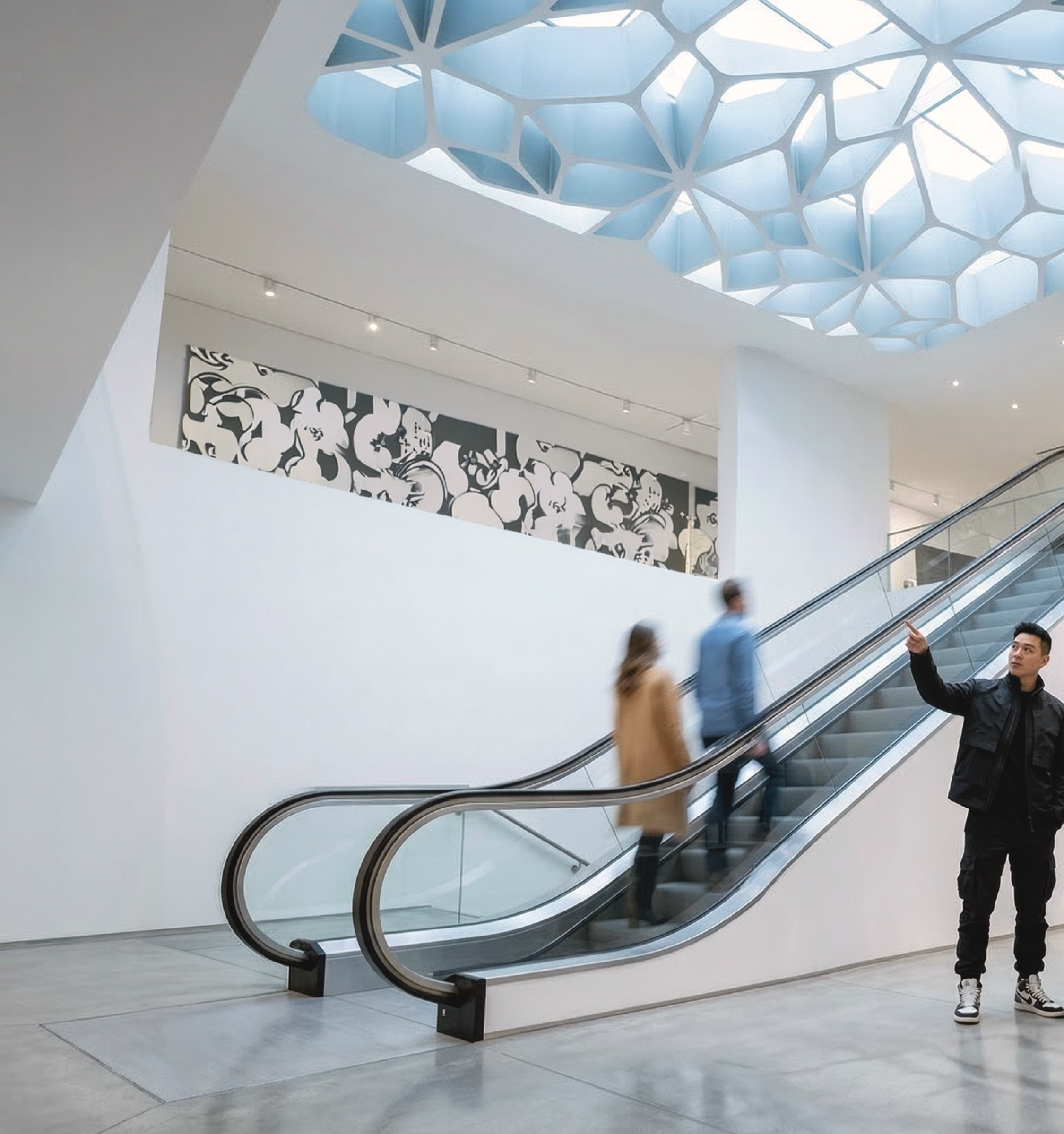 Escalator hall looking up through a Voronoi-patterned skylight canopy glowing with blue daylight, a black-and-white floral art panel on the adjacent wall
