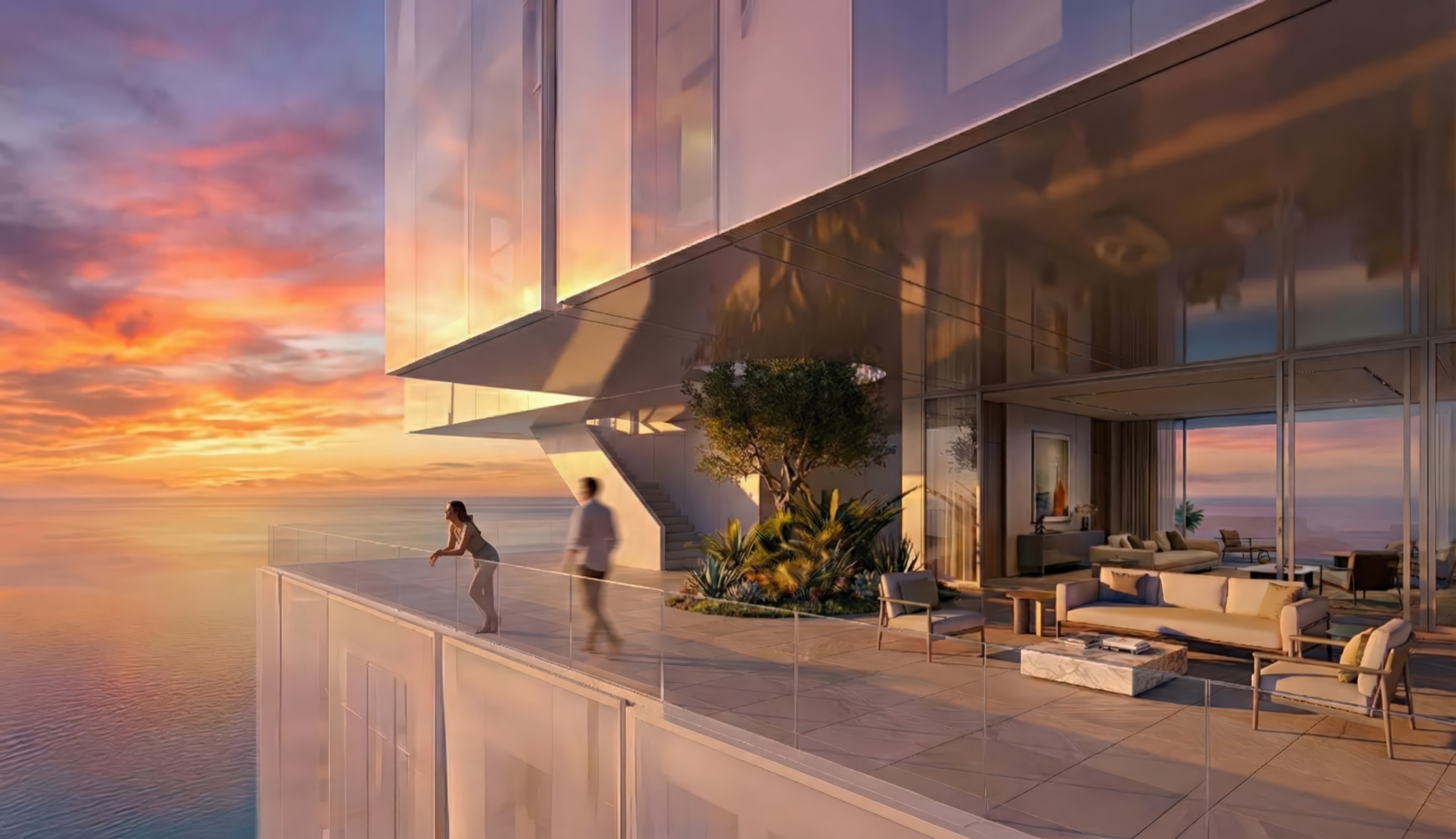Private balcony at sunrise overlooking the Arabian Gulf with outdoor seating, glass balustrade, and the stacked tower volumes visible above