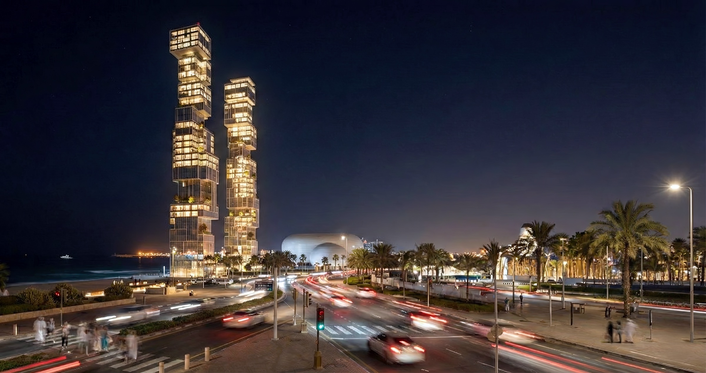 Philips Art Towers illuminated at night from street level with motion-blurred traffic, palm-lined boulevard, and the stacked glass volumes glowing warmly against the dark sky