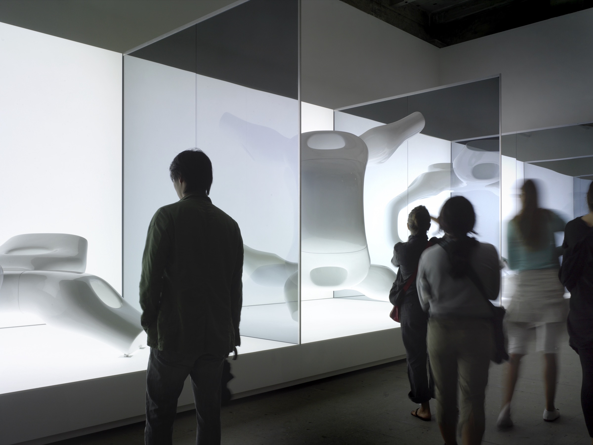 Wide view of the installation in the Corderie dell'Arsenale — M-Scape sculptures on an illuminated plinth behind glass panels, historic brick columns visible