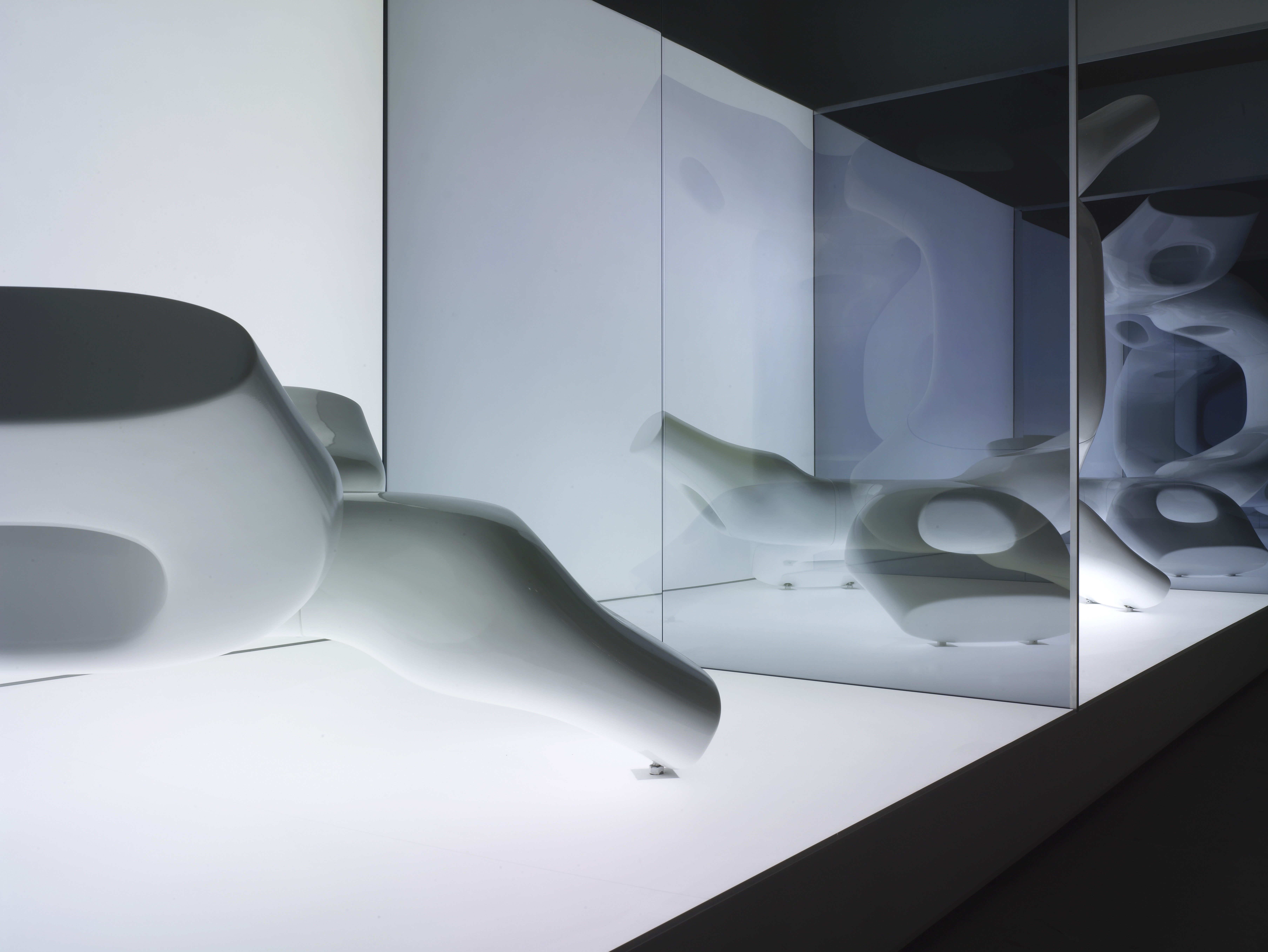 Close detail of an M-Scape sculpture — smooth white fiberglass surface with biomorphic curves reflected in mirrored glass