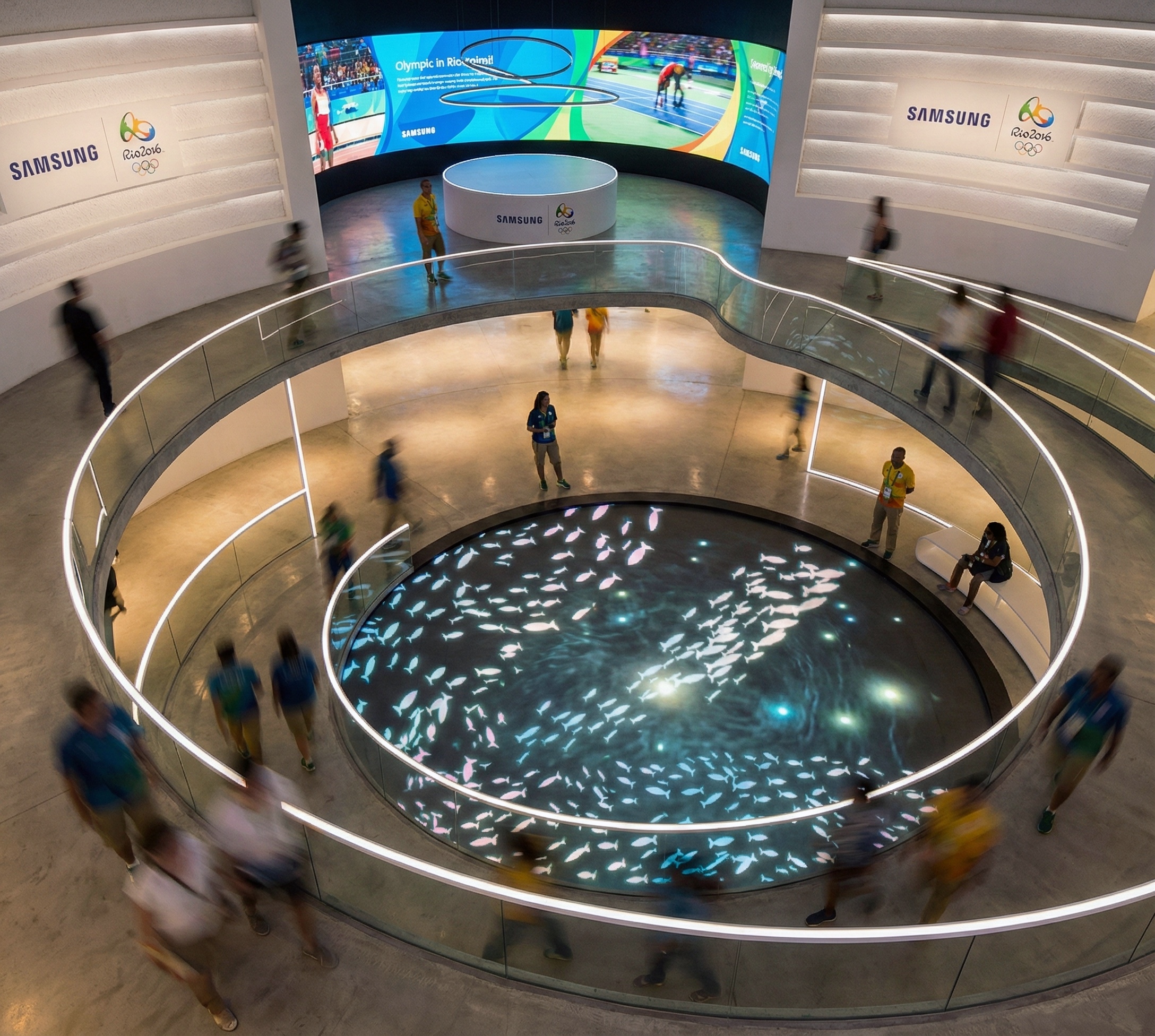 Overhead view of a spiral atrium with visitors circling a central digital pool displaying luminous marine-life projections