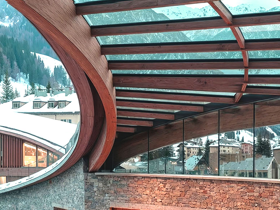 Spa pool with suspended fireplace, curved walnut wall, and mountain views through floor-to-ceiling glass