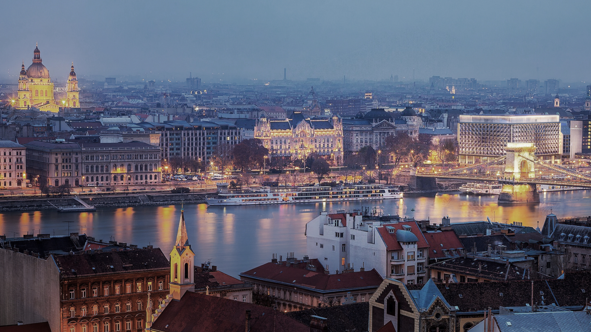 SO/ Budapest Hotel seen from across the Danube at dusk with the Chain Bridge and city skyline