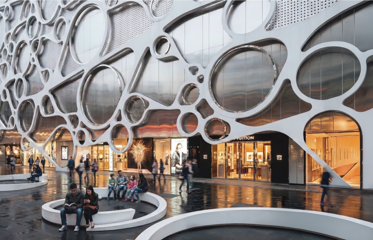 Exterior view of the Taipei Retail Center featuring an organic perforated white facade with circular openings of varying scale framing luxury storefronts