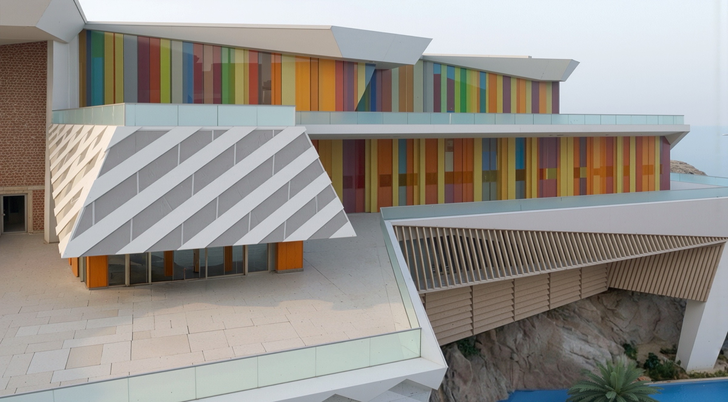 Architectural detail of the resort showing diagonal louver patterns and colorful facade panels with the Red Sea beyond