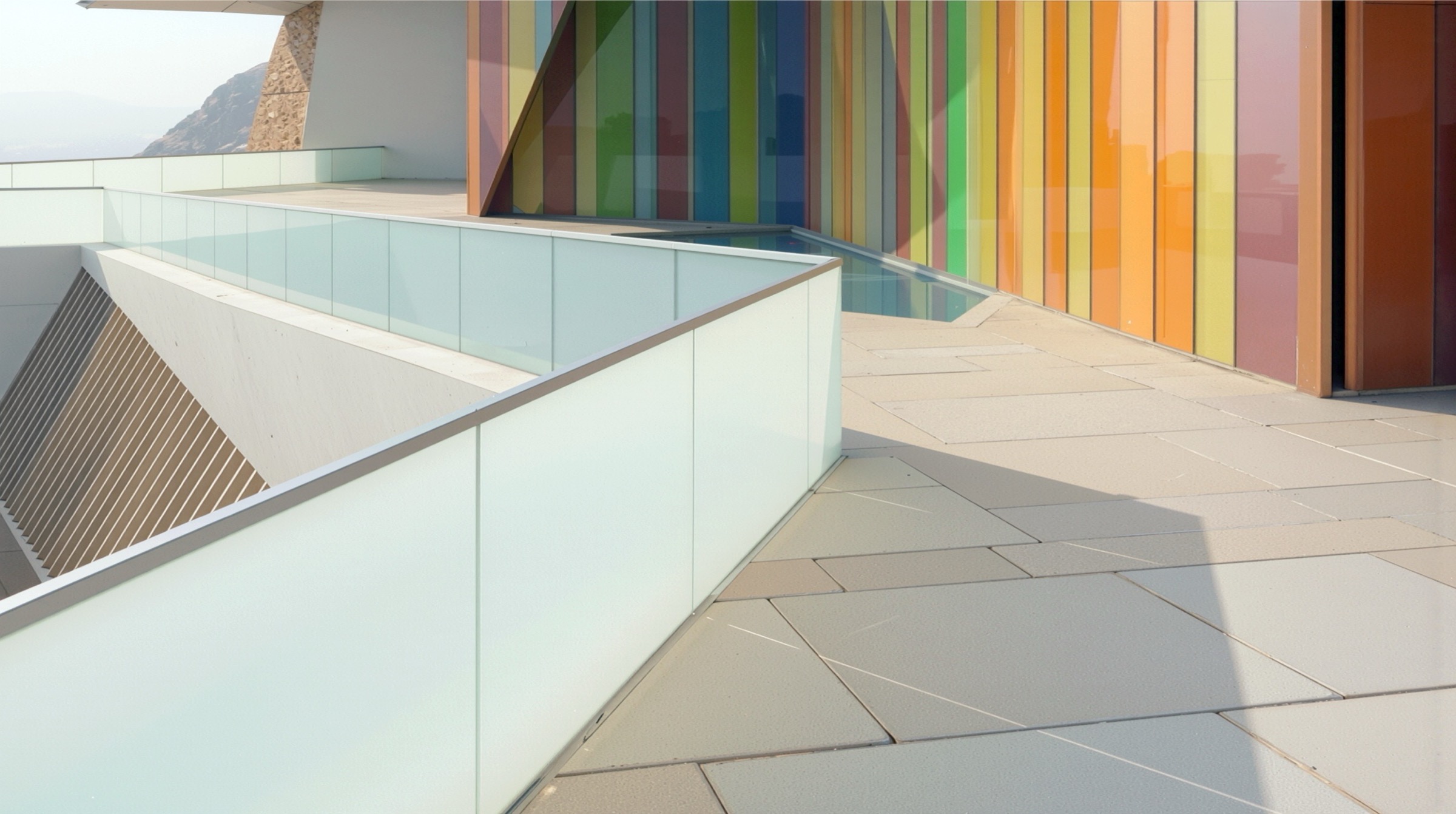 Close-up of pedestrian walkway with glass balustrade alongside colorful translucent facade panels