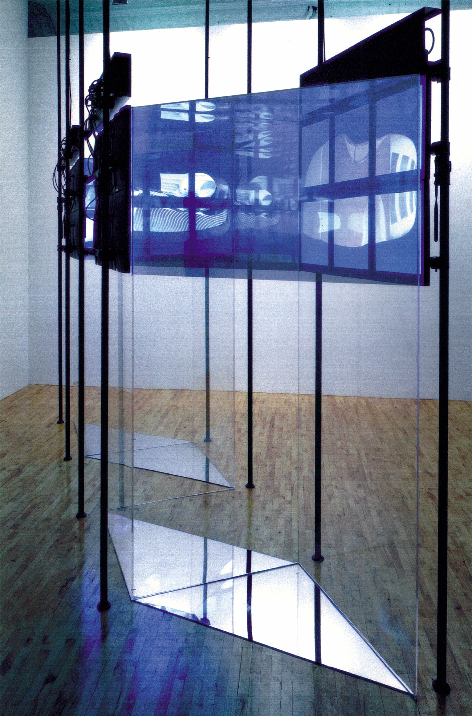 Side view of the FluxSpace 1.0 glass installation — the translucent screen with projected imagery seen between industrial columns and hardware