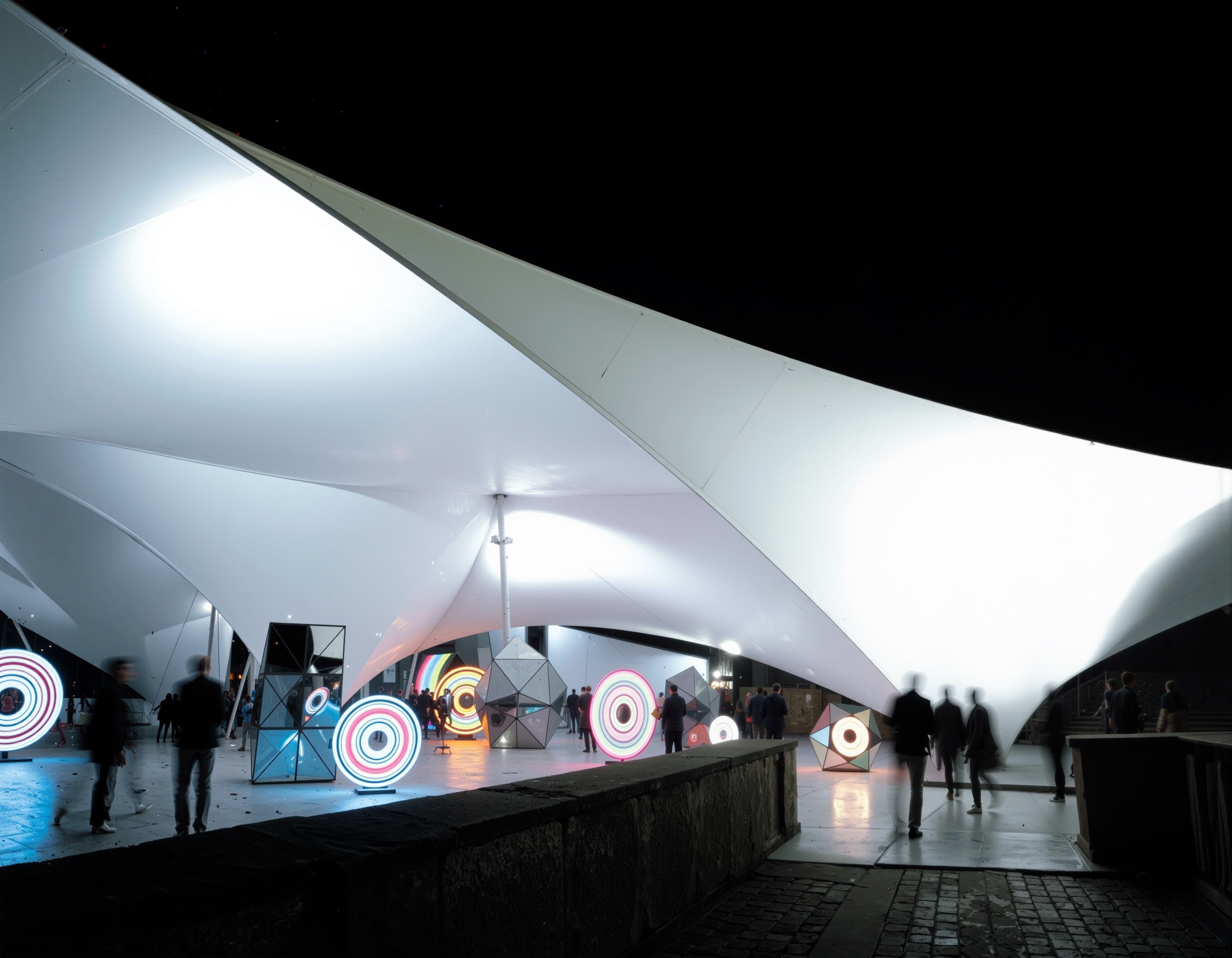 Interior night view of the Univers Theater showing colorful multimedia light installations beneath the tensile canopy