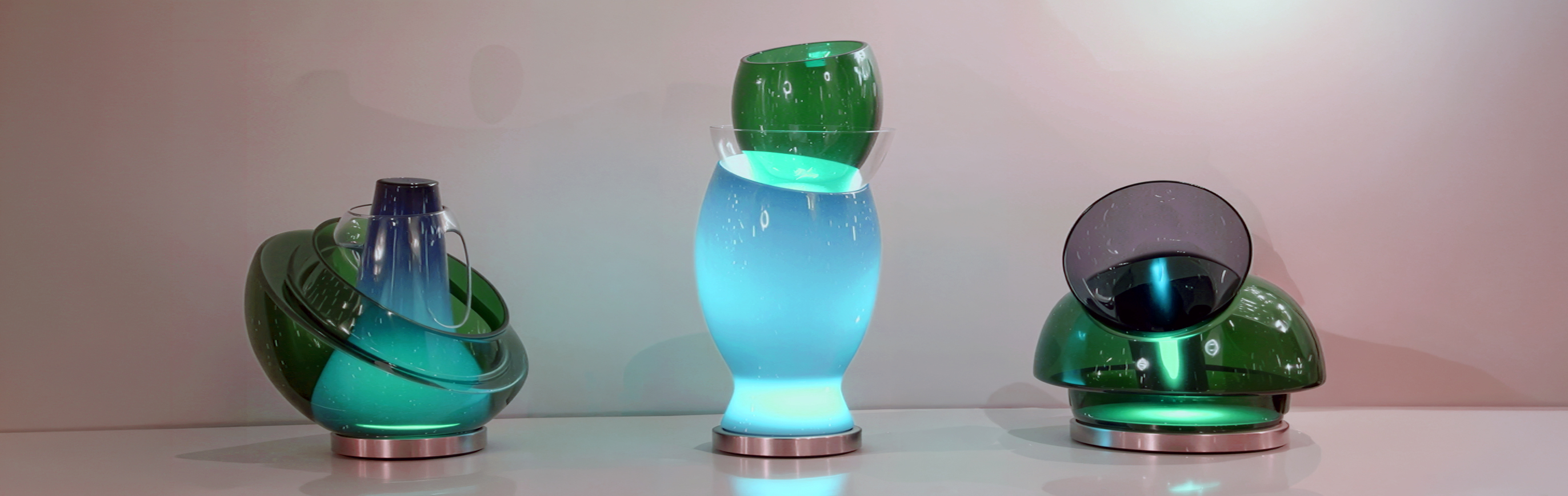 Three illuminated Luminosita glass light sculptures by Asymptote for Venini — green, blue, and emerald pieces lit from within