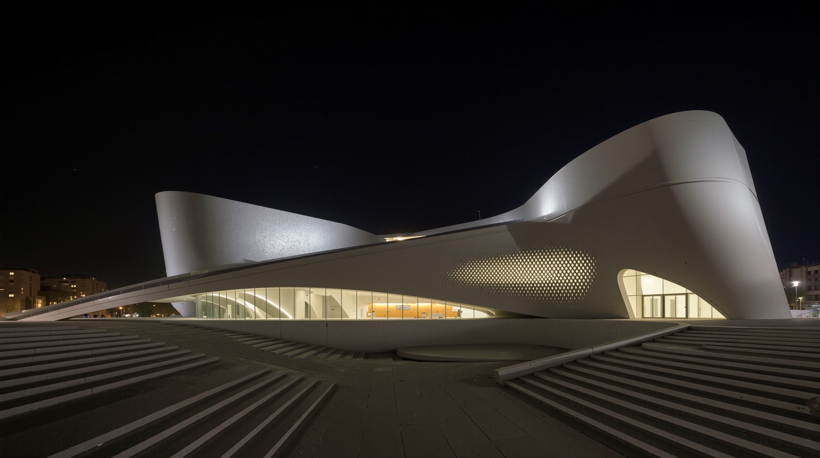 Night view of the museum with interior lighting illuminating the perforated facade from within, creating a lantern-like effect against the dark sky