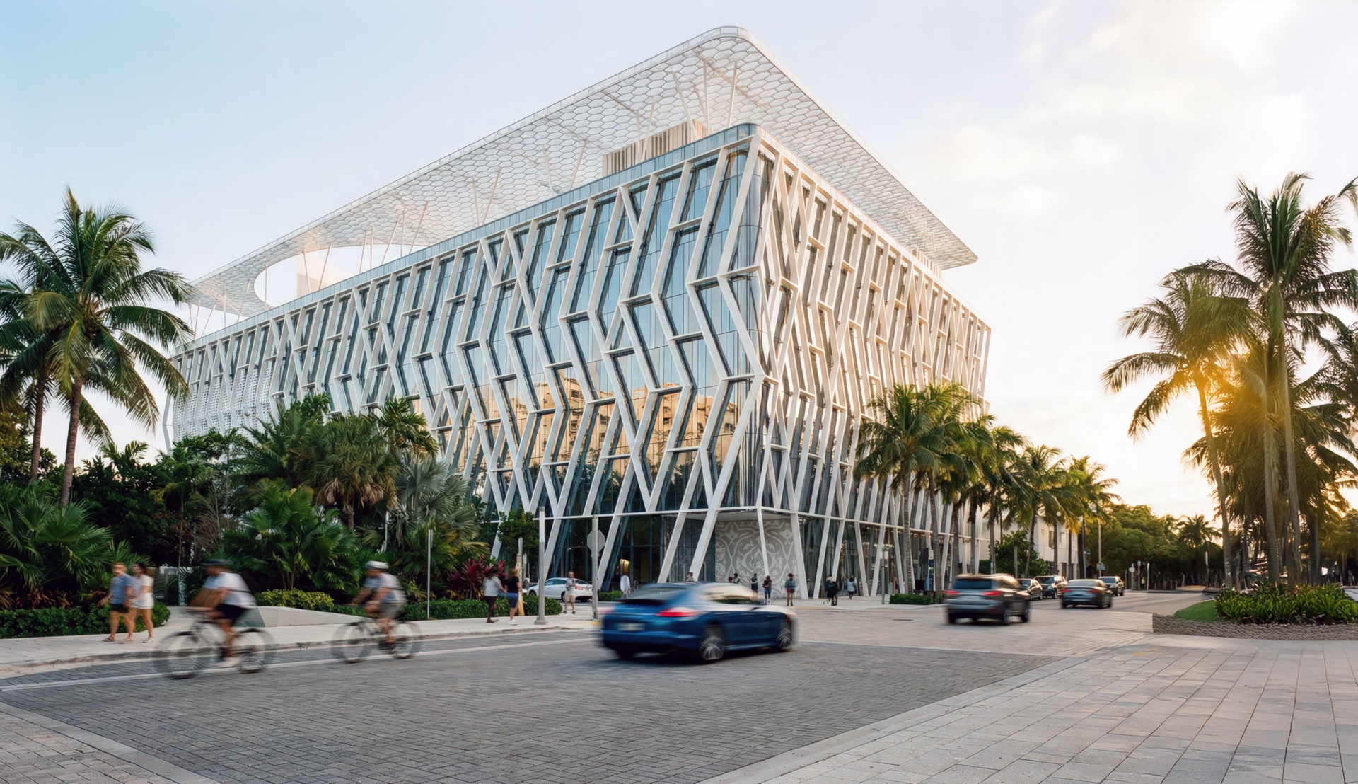 Exterior view of the Vogel Fitness Complex at golden hour surrounded by palm trees, featuring an expressive diagrid structural facade of angled white steel members and glass